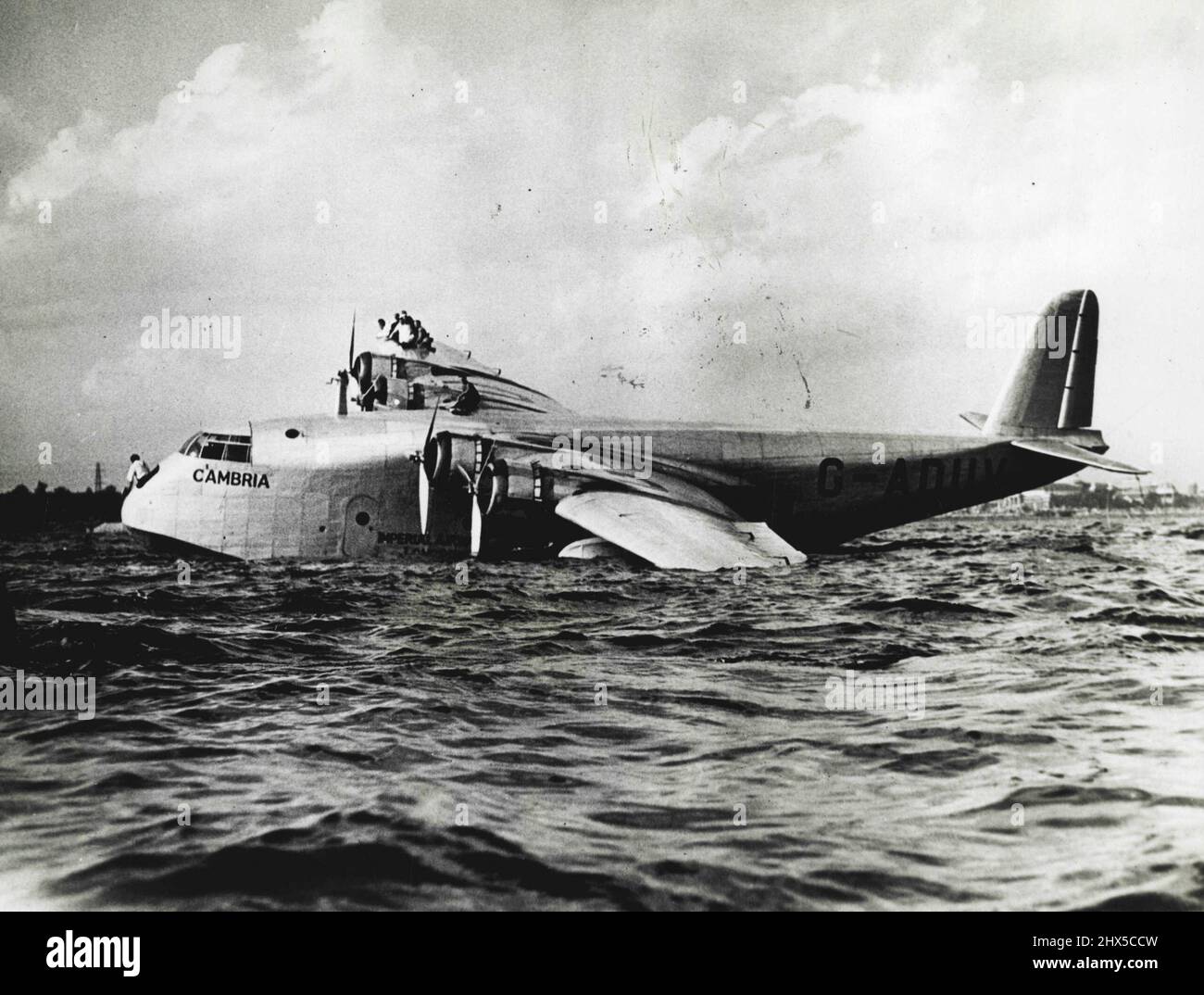 Imperial Airways Schiff stürzt in Toronto ab - Mitglieder der Besatzung auf dem Flügel, als das Boot zum Stillstand trieb. Die Imperial Airways-Flugyacht Cambria, die dreimal erfolgreich den Atlantik überquert hat, stürzte bei ihrer Landung in Toronto, Kanada, am 3.. September ab, als das Gaint-Schiff eine schwimmende Landung traf und ein Loch in einem Ponton riss. Die Besatzung nahm sofort Positionen auf dem rechten Flügel ein, um den beschädigten Ponton auszugleichen und das Schiff vor einer größeren Katastrophe zu retten. 5. September 1937. (Foto von ACME). Stockfoto