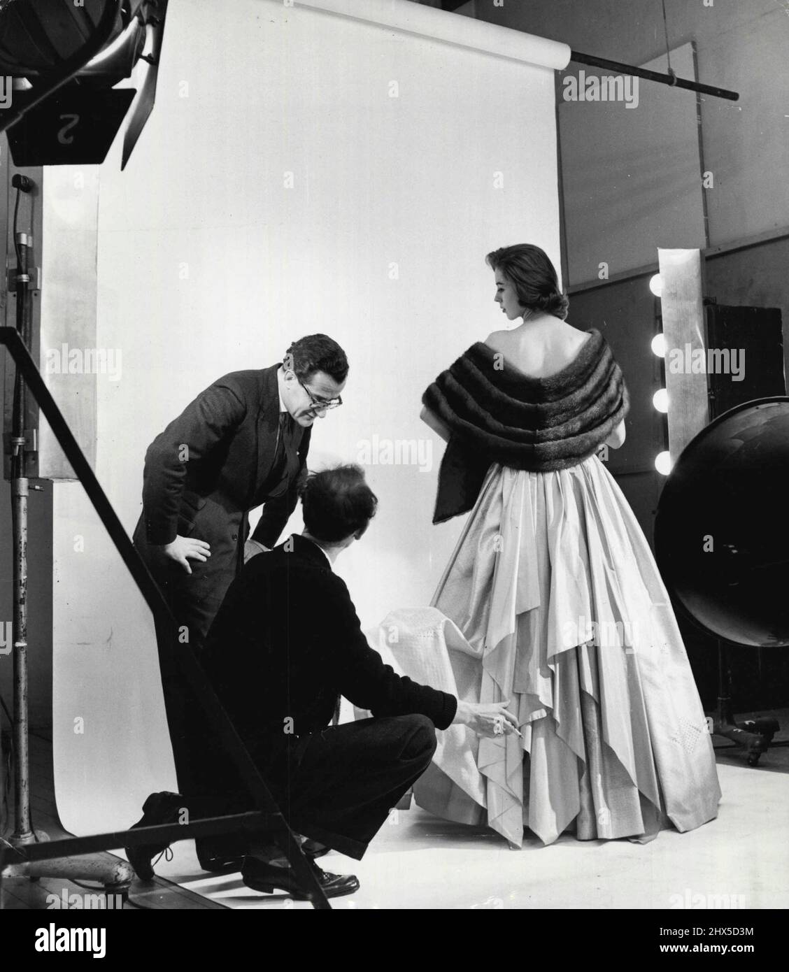 Nachdem sie für einen Anzug ausgestattet wurde, geht Elizabeth mit Peter Langley ins West End-Studio des Fotografen John Cole, wo sie ein mit Fell stahles und trägerloses Abendkleid in verschiedenen Schichten modellieren soll. 27.Mai 1953. (Foto von AGSUP Pictures). Stockfoto