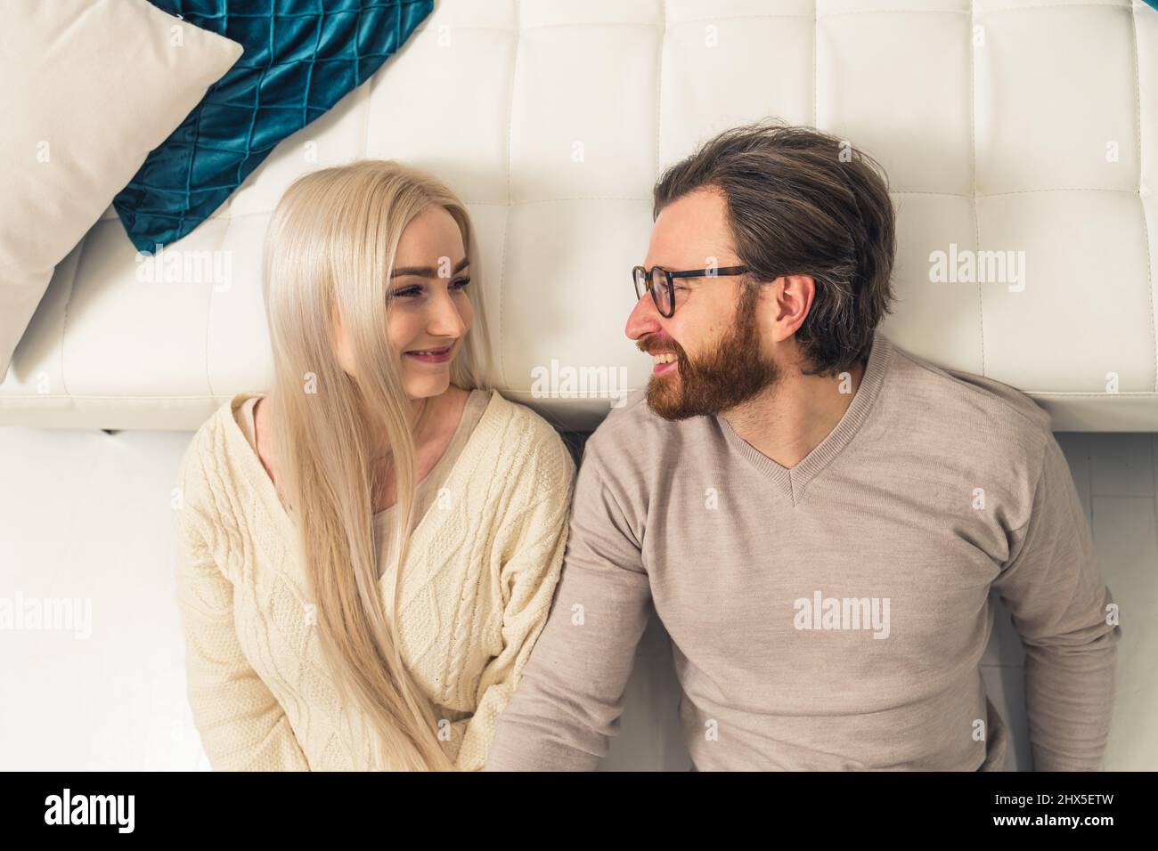 Europäische blonde langhaarige Frau, die sich mit ihrem gebärteten Freund niederlegt und lächelt. Hochwertige Fotos Stockfoto
