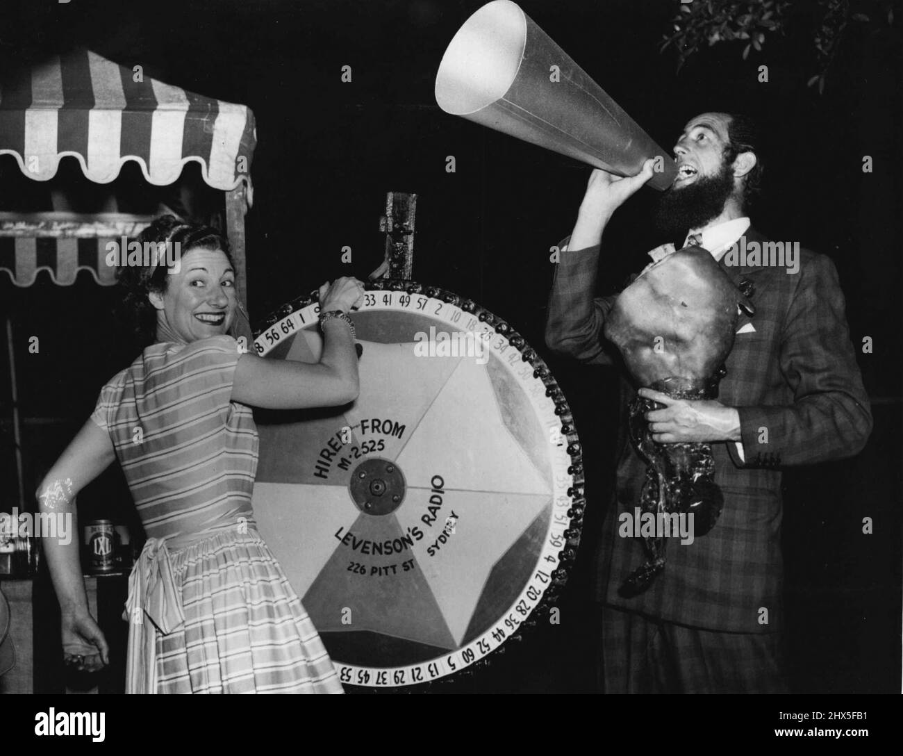 „Chips“ Rafferty und Evie Hayes verkauften Tickets und führten das Schokoladenrad an der Barnecue, die gestern Abend (Sonntag) im Haus von Sam Land statt fand, um Sam Lands Kandidatin Miss Lois Robey bei der „Miss Australia“ Quest zu unterstützen. 01. November 1948. (Foto von J. Tait & A.L. Frazer). Stockfoto
