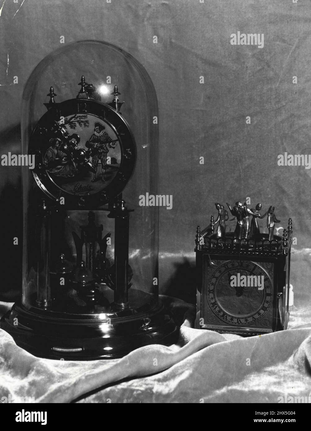 Lebendige Emaillierung auf dem Zifferblatt, Arbeiten und Sockel zeichnen diese 400-Tage-deutsche Uhr aus. Geschützt vor Staub in seiner Glaskuppel, steht es etwa einen Fuß hoch und kostet £13/17/6. 2.Mai 1955. Stockfoto