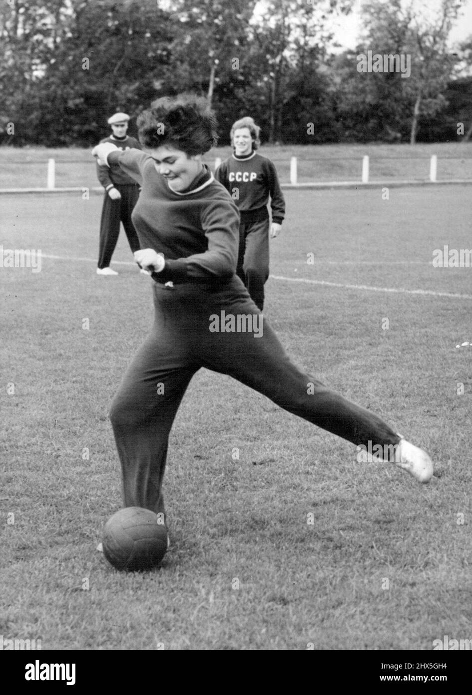 Russische Athleten Üben Für Das Treffen In Der Weißen Stadt. Sogar die russischen Mädchen spielen Fußball. Verve Roolair. Der Speerwerfer, der heute während des Trainings einen Fußball tritt, beobachtet von Marin Itkina. Das Team russischer Athleten, das morgen Abend in der Weißen Stadt ein Londoner Team trifft, trainierte heute Morgen im Motspur Park. 12. Oktober 1954. (Foto von Fox Photos). Stockfoto