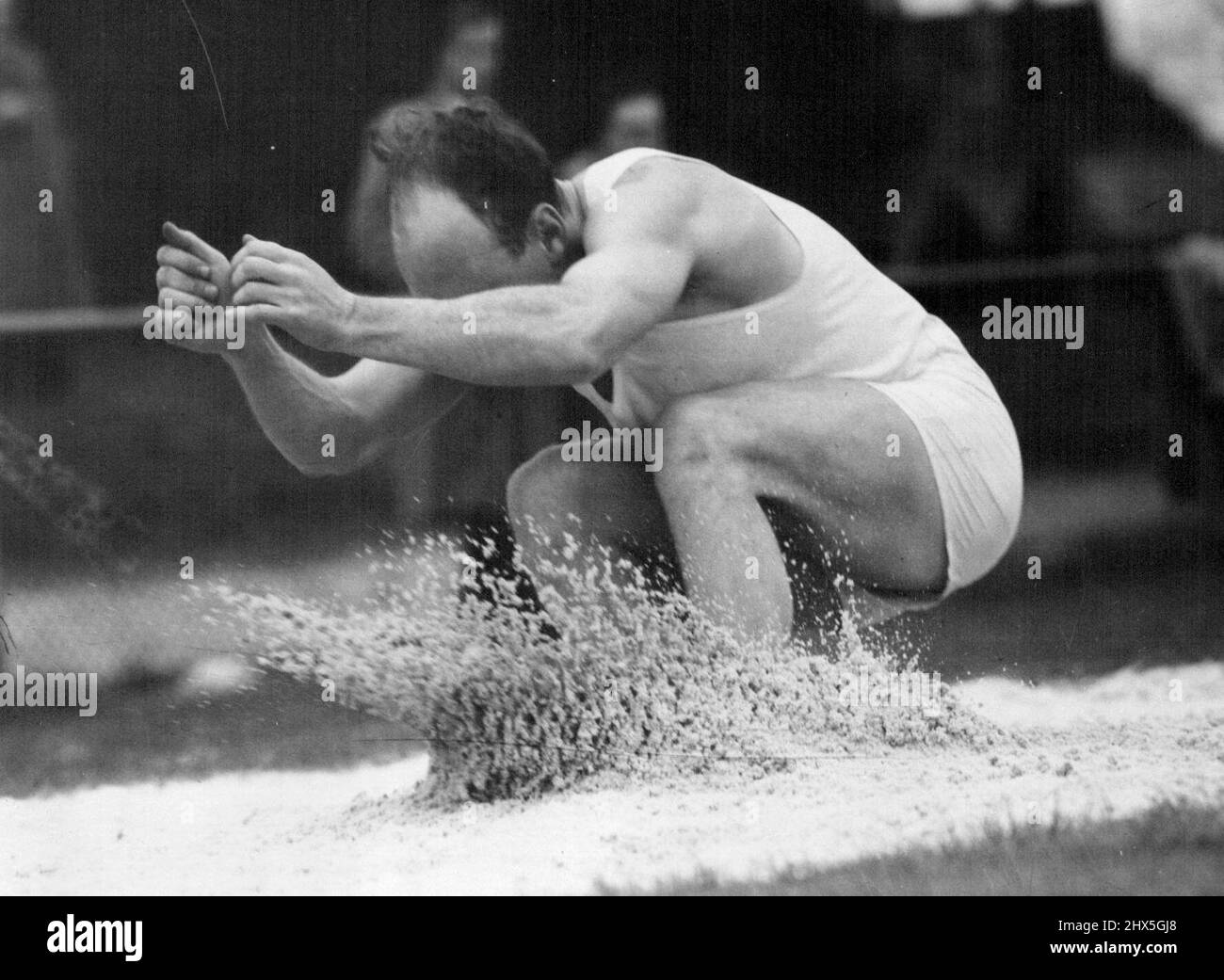 Sand fliegt als B. Burstin, Arme aus und Kopf nach einer 44ft. 1½in. Springen Sie in den Hop, Schritt und ***** Die Universität Oval. 25.Mai 1954. Stockfoto