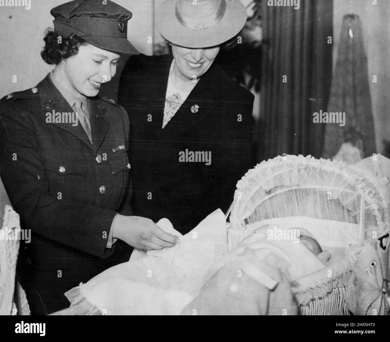 Prinzessin Elizabeth bewundert Babykrippe Prinzessin Elizabeth bewundert eine Babykrippe, die ihr von Frau Water Elliot bei einem Besuch der National Association of Girl Guides in London gezeigt wurde, wo sie im Mai 29 Kleidungsgeschenke aus New South Wales, Australien, erhielt. Die Kleidung wurde dem Queen Charlotte's Hospital und dem Queen Elizabeth Hospital übergegeben. 6. März 1945. (Foto von Associated Press Photo). Stockfoto