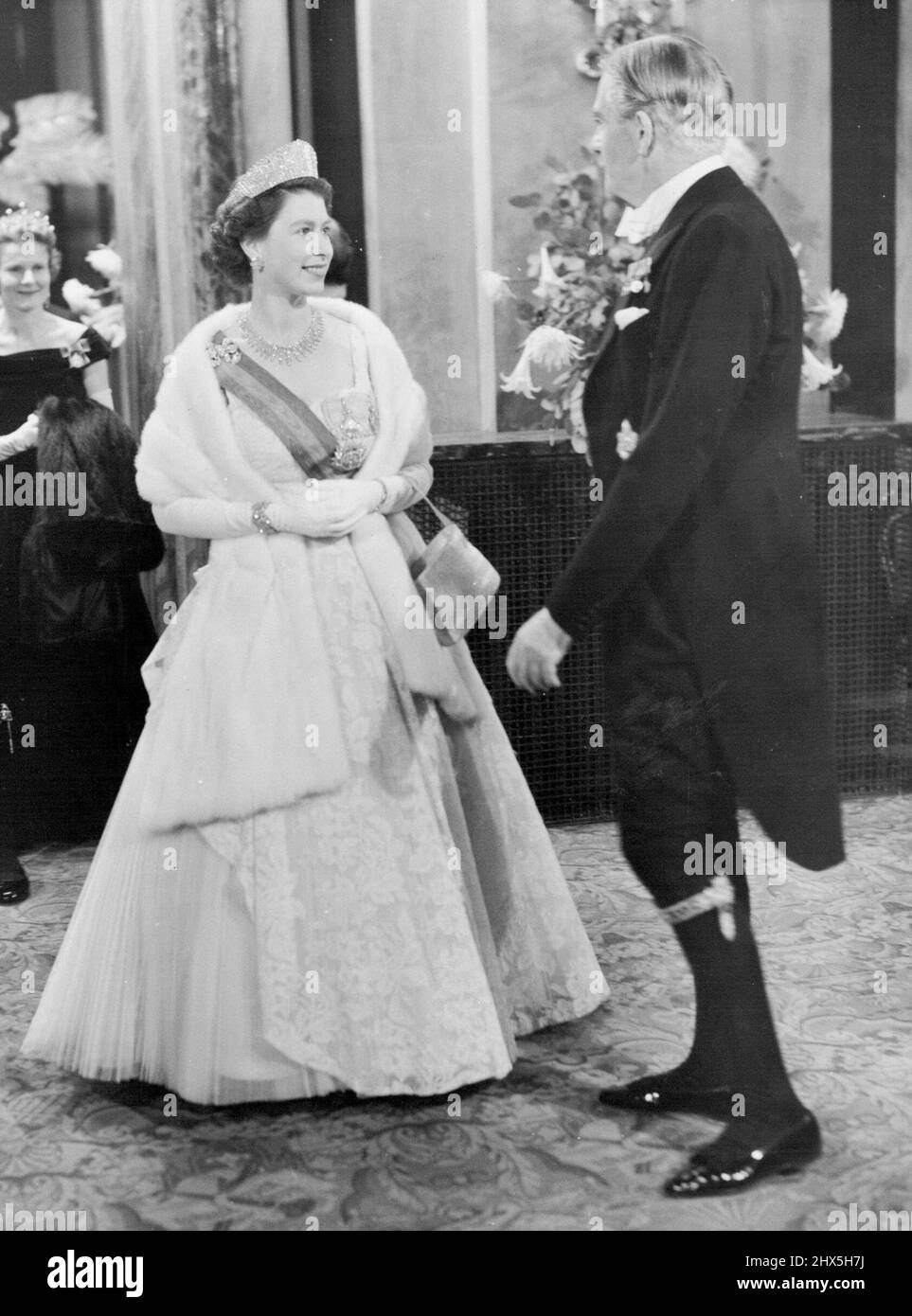 Die Königin An Der Oper. Die lächelnde Königin, strahlend in einem schönen Abendkleid und prächtigem Schmuck, sah gestern Abend im Foyer des Royal Opera House, Covent Garden, im Gespräch mit dem Premierminister Sir Anthony Eden das Kleid eines Ritters der Gartenkünstler tragen. In der letzten Nacht ihres dreitägigen Staatsbesuchs in diesem Land besuchten der Präsident von Portugal, General Craveiro Lopes, und seine Frau Covent Garden, wo sie die Oper "die verbarterte Braut" als Gäste von S.M. der Königin und der königlichen Familie sahen. 28. Oktober 1955. (Foto von Fox Photos). Stockfoto