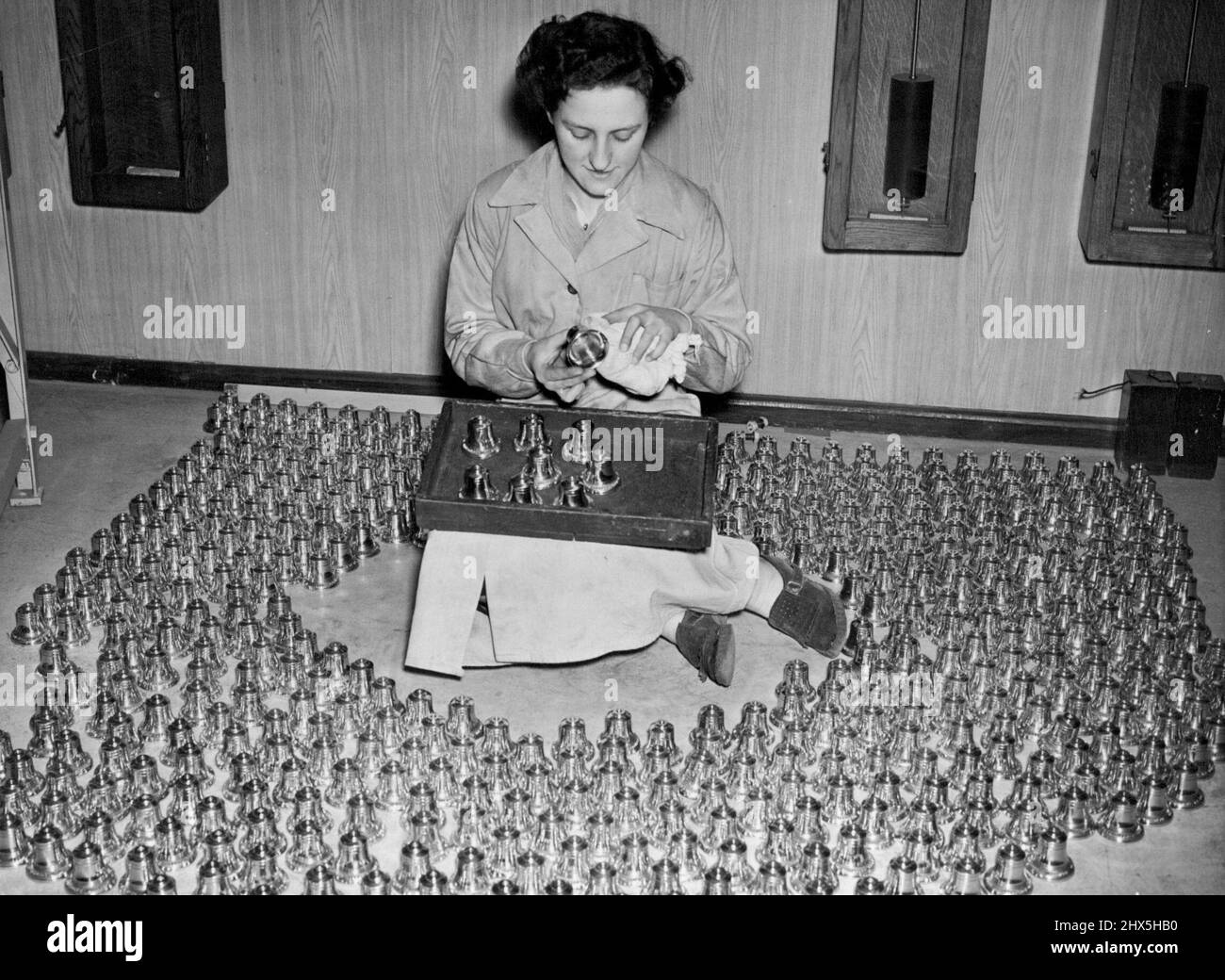 Miniatur-Glocken Für Krönungsartikel. Miss Doreen Smith, 22 Jahre alt, aus South Norwood, umgeben von Hunderten von Miniaturglocken, die sie putzt und inspiziert. In der Gießerei der Herren Gillett & Johnston, Ltd., in Croydon, werden Miniaturglocken aus Metall gegossen, das aus Glocken gewonnen wurde, die zur Zeit von Königin Elizabeth I. gegossen wurden. Sie sind perfekte Repliken und haben eine Krönungsbeschriftung. 17. Februar 1953. (Foto von Fox Photos). Stockfoto