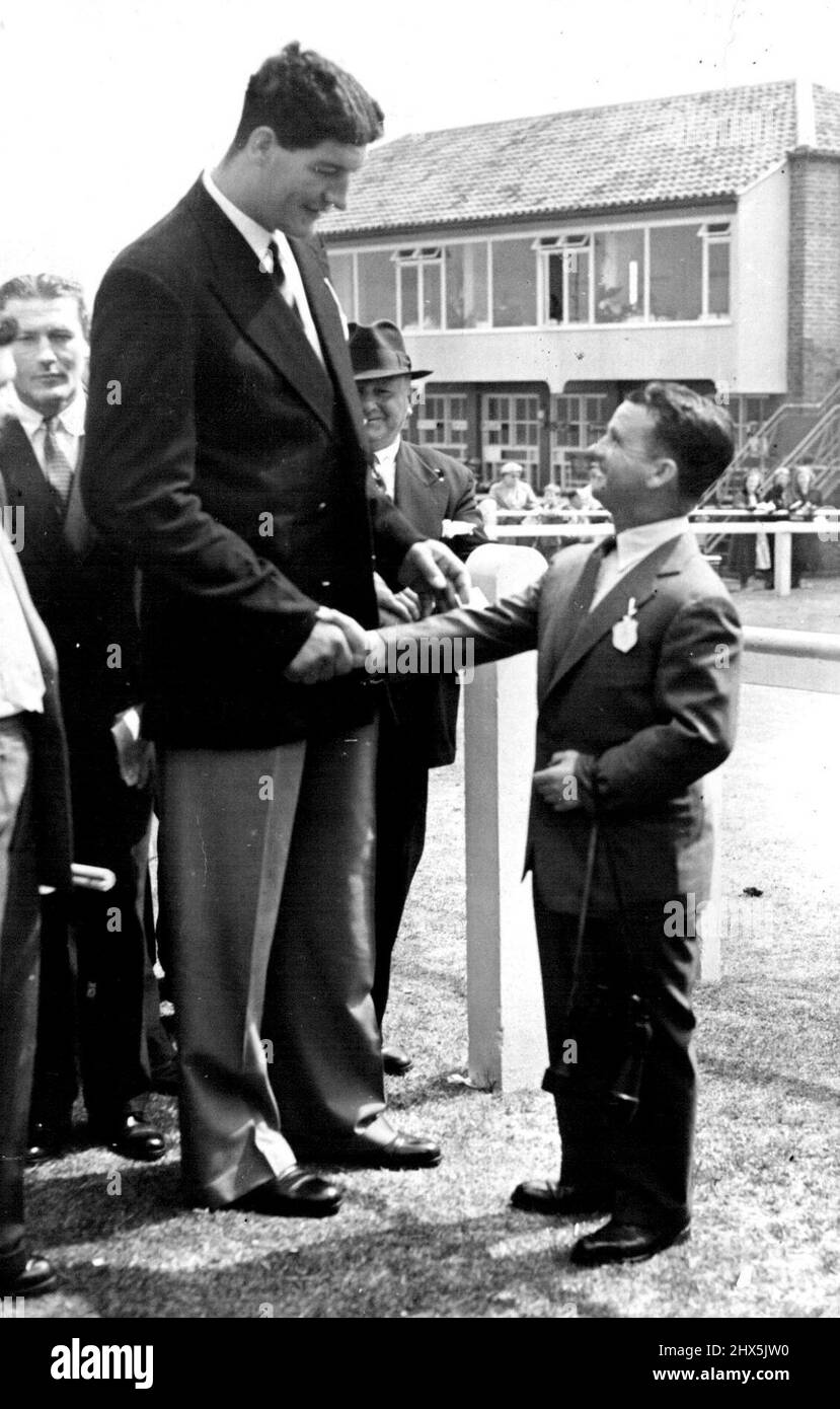 Extreme treffen sich - bei den Rennen Ewart Potgieter, der riesige südafrikanische Schwergewicht-Boxer, der gerade in England angekommen ist und Sir Gordon Richards, ehemals Englands Champion Jockey und jetzt Trainer, die Hände schüttelt, als sie sich beim Renntreffen in Brighton trafen. Potgieter steht 7 Fuß 2 Zoll hoch. 04. August 1955. Stockfoto