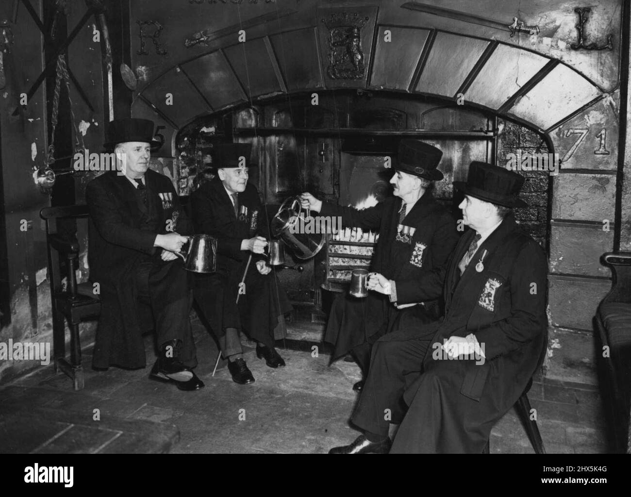Alte Almshusen Englands: Lord Leycester's Hospital. Das Lord Leycester's Hospital, Warwick, wurde 1571 von Robert, Earl of Leycester, gegründet. Unser Foto zeigt vier der Brüder mit den 'Gaudy Cups' aus dem Jahr 1579. Die Tassen werden speziell an vier Tagen der Jollifikationen Oakapple Day, Foundation Day (1. Juli), Guy Fawkes Day und Weihnachten gefüllt. Die Stiftung sieht einen Meister und zwölf ehemalige Soldatenbrüder vor, die die malerischen Kleider und Hüte tragen. Die Abzeichen auf den Kleidern, mit einer Ausnahme, waren die ursprünglich von Lord Leycester gegeben und tragen die Dare 1571 Stockfoto