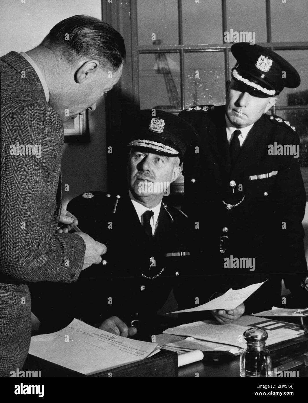 Die Londoner Hafenpolizei die Männer an der Spitze -- sitzen Herr W. H. Simmons, Mitglied des Order of the British Empire und Inhaber der King's Police Medal. Er übergab ihn Mitte 1950 an Herrn S. F. Cox (rechts). Beide sind aus den Reihen der P.L.A. aufgestiegen Polizei. Beide Beamten betrachten die Aufrechterhaltung eines perfekten Standards der Routinearbeit als Grundlage aller Polizeiaktivitäten. Links ist Inspector March, der die Mobile Squad der C.I.D. leitet 01. Juli 1950. (Foto von der Zentrale für Information). Stockfoto