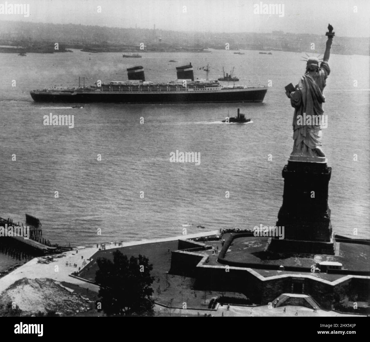 Miss Liberty Waves Bon Voyage -- Amerikas neuestes und größtes Linienschiff -- die Vereinigten Staaten--- kommt gestern an der Freiheitsstatue vorbei und geht auf ihrer Jungfernfahrt nach Europa in Richtung offenes Meer. Der 53.000 Tonnen schwere superliner beförderte 1660 Passagiere auf einer möglicherweise Rekordüberquerung des Atlantischen Ozeans. Der aktuelle Ostrekord wurde 1938 vom britischen Linienschiff Queen Mary aufgestellt, das die Überfahrt in drei Tagen, zwanzig Stunden und zweiundvierzig Minuten machte. 4. Juli 1952. (Foto von AP Wirephoto). Stockfoto