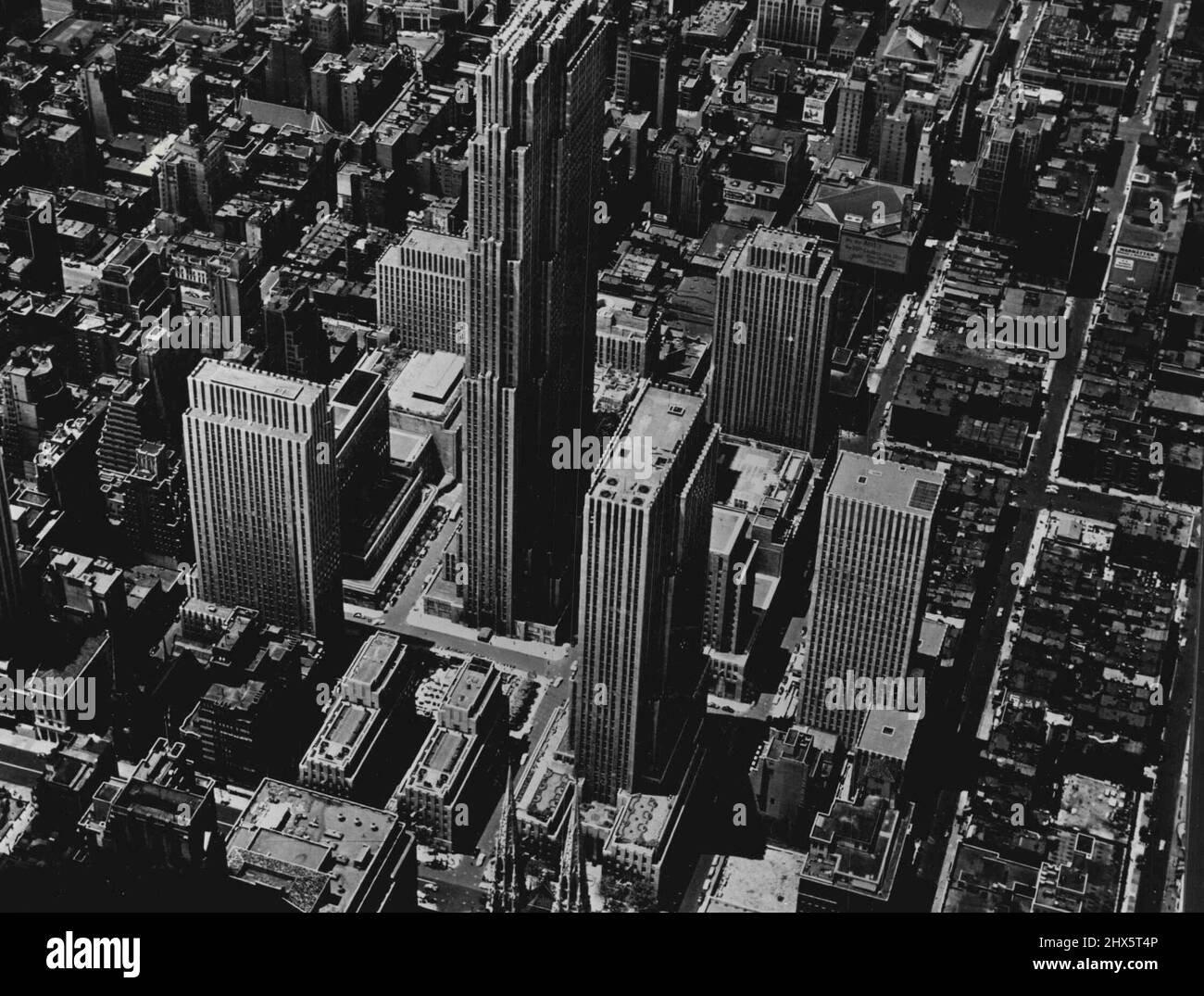 The Rockefeller Center, New York -- Dieses einzigartige 15-Gebäude-Gebäude im Zentrum von Manhattan erstreckt sich über etwas mehr als 12 Hektar zwischen der 48. und 51. Street und zwischen der Fifth Avenue und der Avenue of the Americas. Das Esso-Gebäude, ganz rechts, bildet das nördliche Tor zum Zentrum, mit einem Eingang auf 52.. Das Gebäude in der Mitte des Bildes, das über allen anderen thront, ist das R.A.C. Gebäude mit 70 Stockwerken. Rechts davon, und direkt hinter den Türmen der St. Patrick's Cathedral, befindet sich das 41-stöckige International Building. Das 36-stöckige Time and Life Building steht am Stockfoto