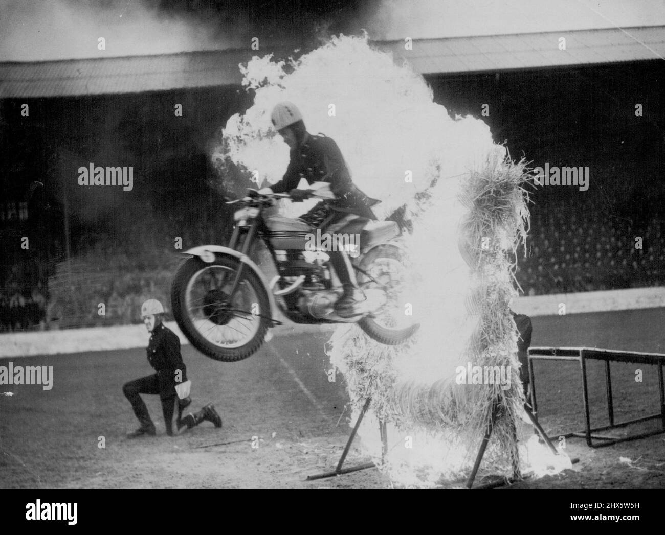 Fire Flyer - Zuschauer können ***** bekommen Unter dem Kragen, aber dieser wagemutige Army-Motorradfahrer ist absolut cool, als er einen spektakulären Flug durch eine Barriere aus brüllender Flamme macht. Er ist Mitglied des Royal Signals Motor-Cycle. Display-Team und ist während einer Generalprobe im Catterick Camp, Yorkshire, abgebildet. Das Team wird beim Northern Command Tattoo vom 28. Juni bis 3. Juli im Roundhay Park Leeds, Yorkshire, zu sehen sein. 08.Mai 1954. (Foto von Reuterphoto). Stockfoto