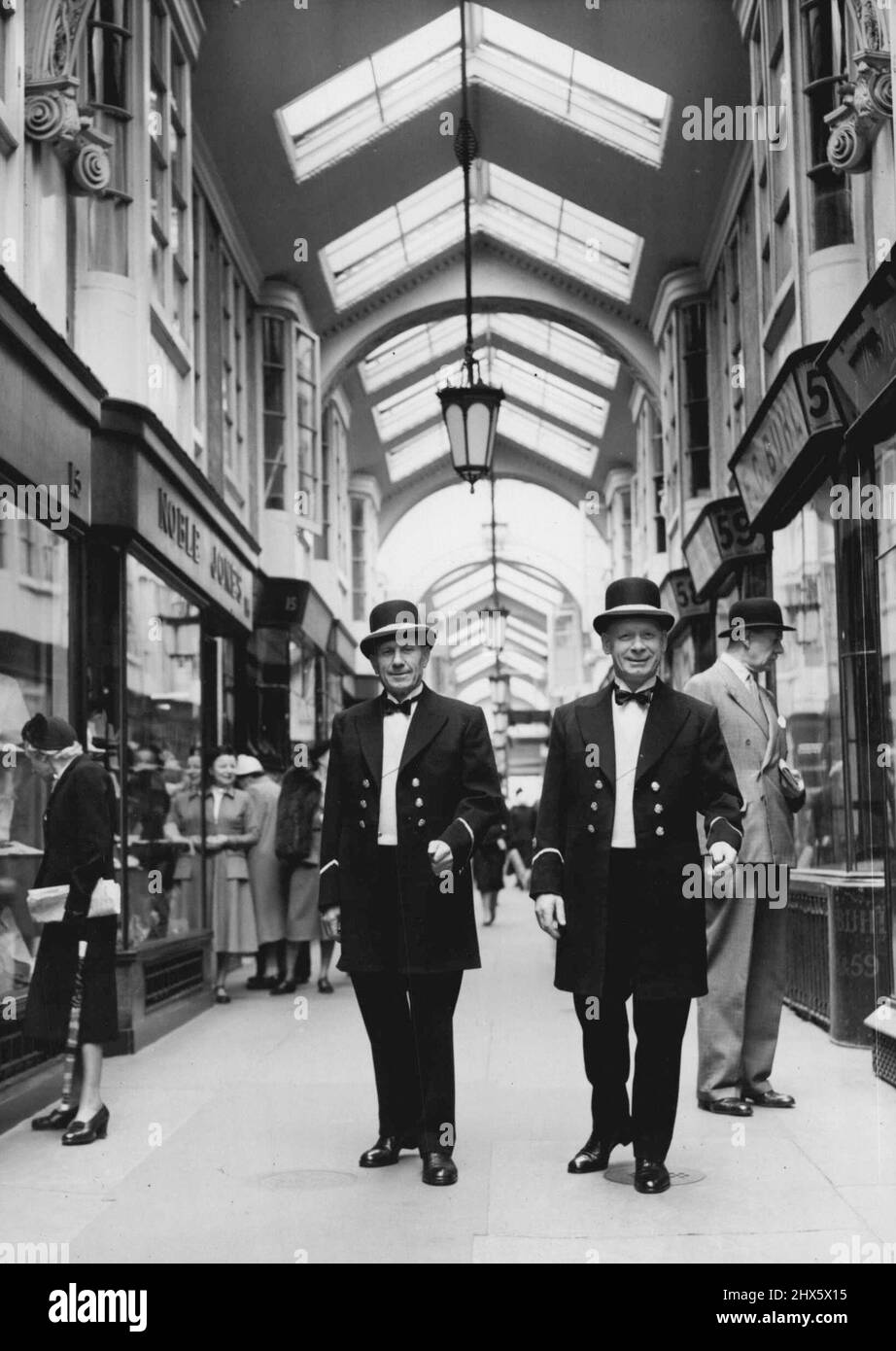 Neue Uniformen für Burlington Arcade Beadles -- die beiden Perlen, die heute zum ersten Mal ihre neuen Uniformen tragen, fotografierten den Spaziergang in Burlington Arcade. Es handelt sich (links) um Herrn Frank Clark von Fulham und Chief Beadle Robert Baker von Stockwell. Die beiden Perlen, die jeden Tag um 5-30 Uhr in der berühmten Burlington Arcade die 100 Jahre alte Glocke läuten, haben gerade neue Uniformen erhalten, die sie im Sommer tragen werden. Hergestellt von Sam Fisher, einem Schneider in The Arcade, mit Olds Prints Stockfoto