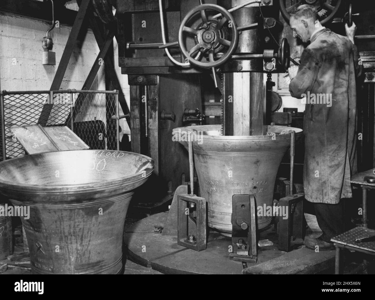 British Bells sind auf der ganzen Welt zu hören -- Eine 13cwt-Tenorglocke für Rockhampton (Australien) in der Stimmmaschine. Auf der linken Seite befindet sich eine Glocke von 10cwt nach Stamford (USA). In der berühmten Croydon-Fabrik der Herren Gillette und Johnson sind Arbeiter damit beschäftigt, Glocken für Kirchen und Uhrtürme in allen Teilen der Welt zu gießen und zu stimmen. 31. Oktober 1946. 31. Oktober 1946. Stockfoto