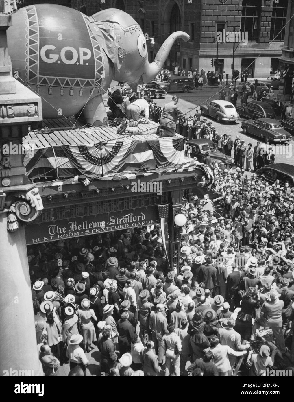 The Mob Follows the Elephant – Hier ist ein Teil der Menschenmenge, die sich vor dem Bellevue-Startford Hotel in Philadelphia, Pennsylvania, im Juni 20 versammelt hat, um Govdewey und andere republikanische Berühmtheiten bei der Ankunft zur Nationalversammlung zu beobachten. Der Ballonelefant auf dem Festzelt des Hotels, der unter verschiedenen Deflationsstadien litt, ist nach einem Pumpenjob wieder auf den Beinen. 20. Juni 1948. (Foto von Associated Press Photo).;The Mob folgt dem Elefanten -- Hier ist ein Teil der Menge, die sich vor dem B versammelt hat Stockfoto