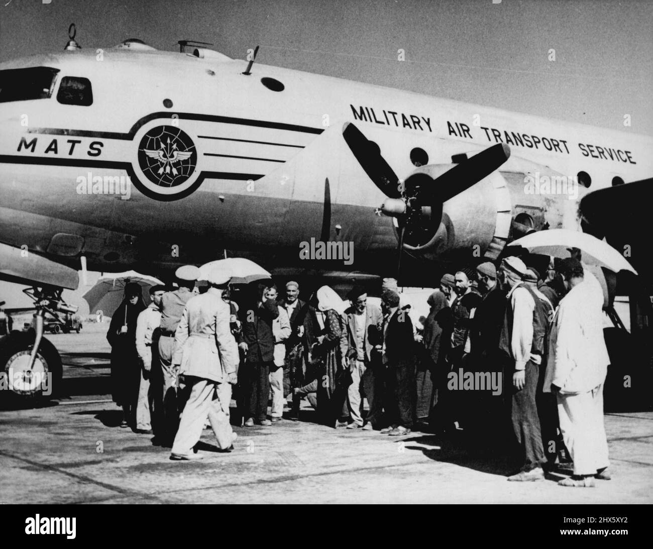 Mekka Air Lift -- muslimische Pilger aus der Türkei besteigen ein Flugzeug der US Air Force in Beirut, Libanon. Das Flugzeug war eines von 14 Transportflugzeugen der US-Luftwaffe, die zur "Mekka-Luftbrücke" für Pilger gebracht wurden, die in Beirut ohne Flugunterkunft gestrandet sind die meisten Pilger tragen einen Regenschirm, weil sie nach der Landung in Jeddah ihre Hüte für die Dauer der Pilgerfahrt wegwerfen müssen. Sonnenschirme sind nicht verboten. Das Bild wurde Anfang dieser Woche gemacht. 30. August 1952. (Foto von Associated Press Photo) Stockfoto