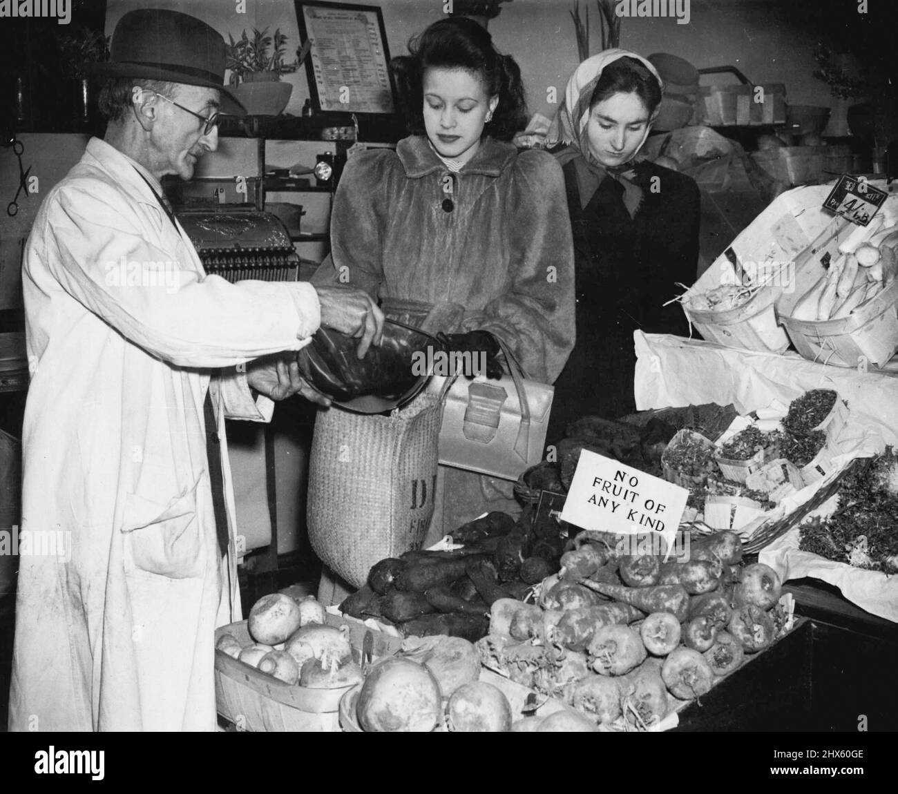 Londoner Hausfrau 1946. Kartoffeln gibt es in der Regel reichlich: Gleich an der Straße von der Frau des Lebensmittelhänders (Jill bekommt 71b. Von Kartoffeln von ihrem Gemüsehändler, Herrn Ferraro, „Keine Früchte jeglicher Art“ sagt die Karte (alle Karten sagen „Nein“), was Frau Gill erwartet hat. Orangen kommen alle paar Monate neu, Babys bekommen ein Pfund auf ihre Grünbücher und was übrig bleibt, geht an die Erwachsenen, die erste Schiploade von Bananen (ein halbes Pfund für unter Achtzigern) hat gerade London erreicht. 12. Juli 1950. (Foto Stockfoto