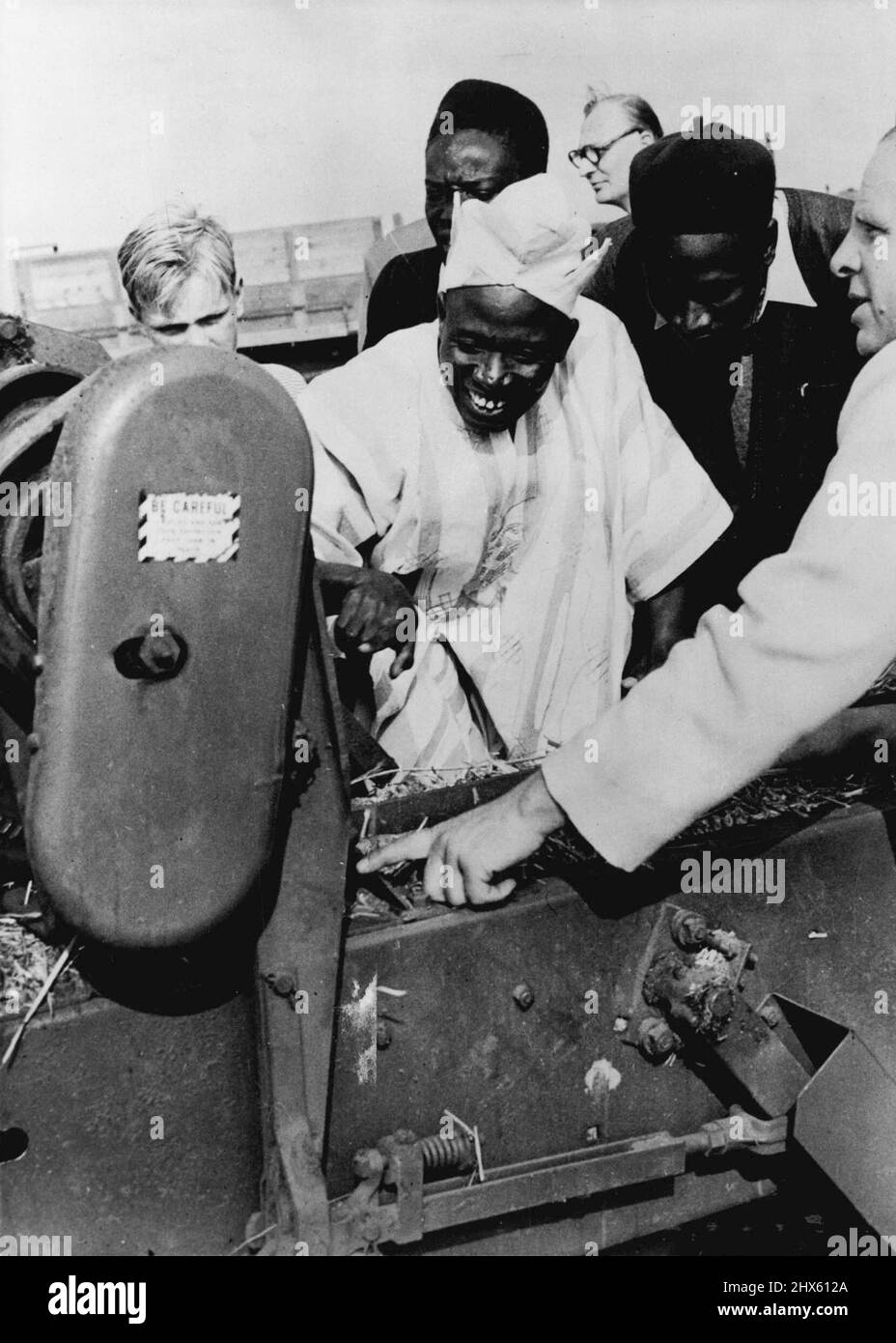 Afrikanische Chieftains In Die Wunder Der Modernen Landwirtschaft Eingeführt -- Ein Kontrast in den Ausdrücken von 2 der besuchten Chieftains aus Nordien, als Herr G. C. Spencer, der Landwirt, die Arbeit einer Strohballenpresse erklärt, die einem Mähdrescher bei der Arbeit auf einem Haferfeld auf der Springdale Farm, Rudston, in der Nähe von Bridlington (Yorks) folgte. Eine Woche lang in Yorkshire zu verbringen, um Landwirtschaft und Anbaumethoden zu studieren, ist eine Party von Northern ian Chieftains. Vor kurzem besuchten sie Herrn G.C. Spencer’ Stockfoto