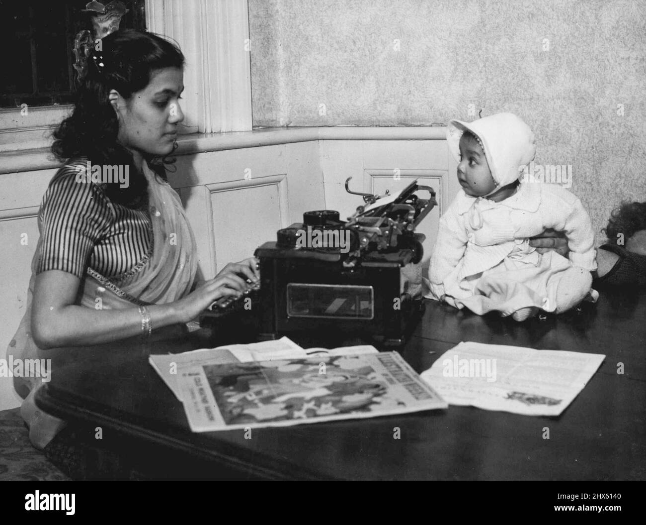 Alles, was sie erfährt, wird sie weitergeben -- Mrs. Ruby Majarika, 21, wird von ihrem vier Monate alten Baby Niva beobachtet, während sie im International Language Club, Croydon, Surrey, auf ihrer Schreibmaschine zusammenklattert. Ruby kam vor achtzehn Monaten aus dem Dschungel von Assam nach England, während ihr Mann das Londoner Verkehrssystem studiert, nimmt sie an einem Sekretariatskurs Teil. Als sie nach Assam zurückkehren, plant Ruby, die erste Kurzschrift-Schule zu gründen, um ihr Wissen an Mädchen in der Provinz weiterzugeben. 12. April 1950. ( Stockfoto