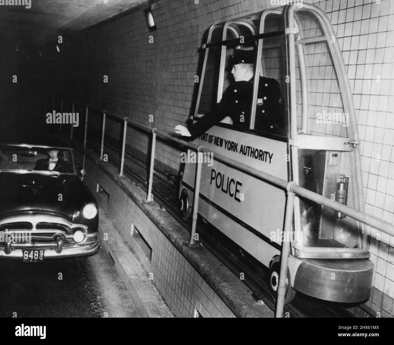 Ein elektrisch angetriebenes Streifenwagen rollt auf dem Laufsteg eines Abschnitts der New Yorker U-Bahn des Holland Tunnels entlang von Miniatureisenbahnen während eines kürzlich von der Port of New York Authority durchgeführten Tests. Wenn die Betriebstests erfolgreich sind, ersetzt das Auto die Fußpatrouillen, und vier anstatt sechs Patrouillen können den Tunnel patrouillieren. 15.Mai 1965. (Foto von Associated Press Photo). ;Ein elektrisch betriebenes Streifenauto rollt auf dem Laufsteg eines Abschnitts des New Y entlang von Miniatureisenbahngleisen Stockfoto