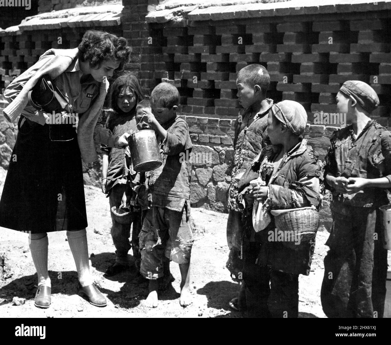 Nichts verschwendet -- Ein zerfetzter kleiner Junge aus dem Dorf Li Chuan zeigt Ann Cottrell aus Richmond, VA., UNRRA China-Korrespondentin, wie viel Mehl er während der Verteilung von freiem UNRRA-Mehl an die Dörfer durch CNRRA vom Boden geschabt hat. 24. Juni 1946. (Foto von Michael Arthur/Fairfax Media).;nichts verschwendet -- Ein zerfetzter kleiner Junge aus dem Dorf Li Chuan zeigt Ann Cottrell aus Richmond, VA., UNRRA China Korrespondentin, wie viel Mehl er während des Verteilenden vom Boden geschabt hat Stockfoto