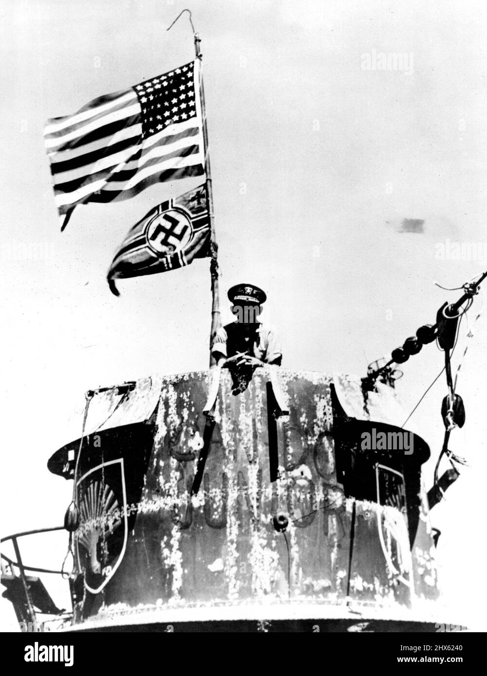 US Navy Schiffe vor Westafrika - Captain Daniel V. Gallery, Kommandant der US-Arbeitsgruppe, die die U-505 eroberte, wird auf dem Turm des deutschen Unterseebades fotografiert. Entsprechend dem Marineanbau fliegen die US-Farben über dem Nazi-Emblem, das die Nationalität des gefangenen Schiffes bezeichnet. 22. Juni 1945. (Foto vom US Office of war Information Picture).;U.S. Marine Schiffe vor Westafrika - Kapitän Daniel V. Gallery, Kommandant der US-Arbeitsgruppe, die die U-505 erobert hat, ist Ph Stockfoto