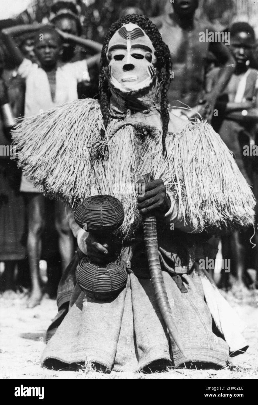 Congo Folklore -- einer der etwa zwanzig Charaktere im Mbuya-Tanz des Bapende-Stammes... Ein afrikanisches Folklore-"Spiel". Er trägt eine weiß gestrichene Maske, Pigtails, und trägt einen Korb mit getrockneten Samen und einem Antelope-Horn. Die Folklore Afrikas liegt nicht in Büchern, sondern in den rhythmischen Tribal-Tänzen, die von Generation zu Generation weitergegeben werden. Die Ursprünge der Tanzschritte, die Gesten und die manchmal ängstlich aussehenden Kostüme liegen tief in der Vergangenheit und beschäftigen sich mit Dürre und Regen Stockfoto