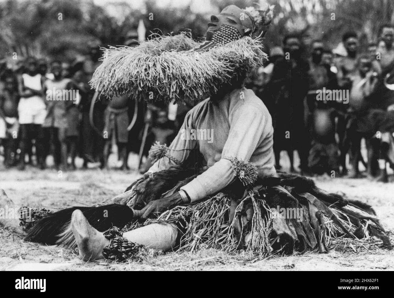 Kongo Folklore -- Ein müder 'Kore' ruht nach einer Aufführung im Mbuya-Tanz des Bapende Tribe. Dieser Tanz ist ein afrikanisches Folklore-"Spiel" mit bis zu zwanzig Charakteren. Kore ist die Personifizierung der Antilope. Er ist wichtig bei der Aussaat und Ernte, wenn er den Segen der Götter fordert. Er trägt einen Rock aus Bast und Affenfellen, bärtige Maske und trägt einen Antilopenschwanz. Er tanzt mit antielpenähnlichen Sprüngen. Die Folklore Afrikas liegt nicht in Büchern, sondern im rhythmischen Tri Stockfoto