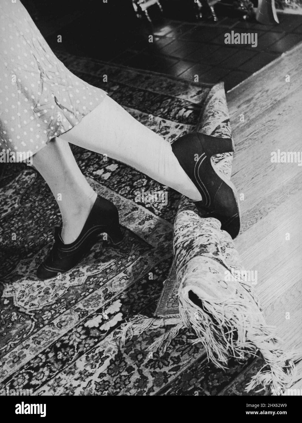 Verankern Sie kleine Teppiche oder Ecken großer Teppiche. Kleine auf gewachsten Böden rutschen leicht und pitchen für gefährliche Tumbles Homefolks. 25. November 1939. (Foto von Warner Wolff, Camera Features). Stockfoto