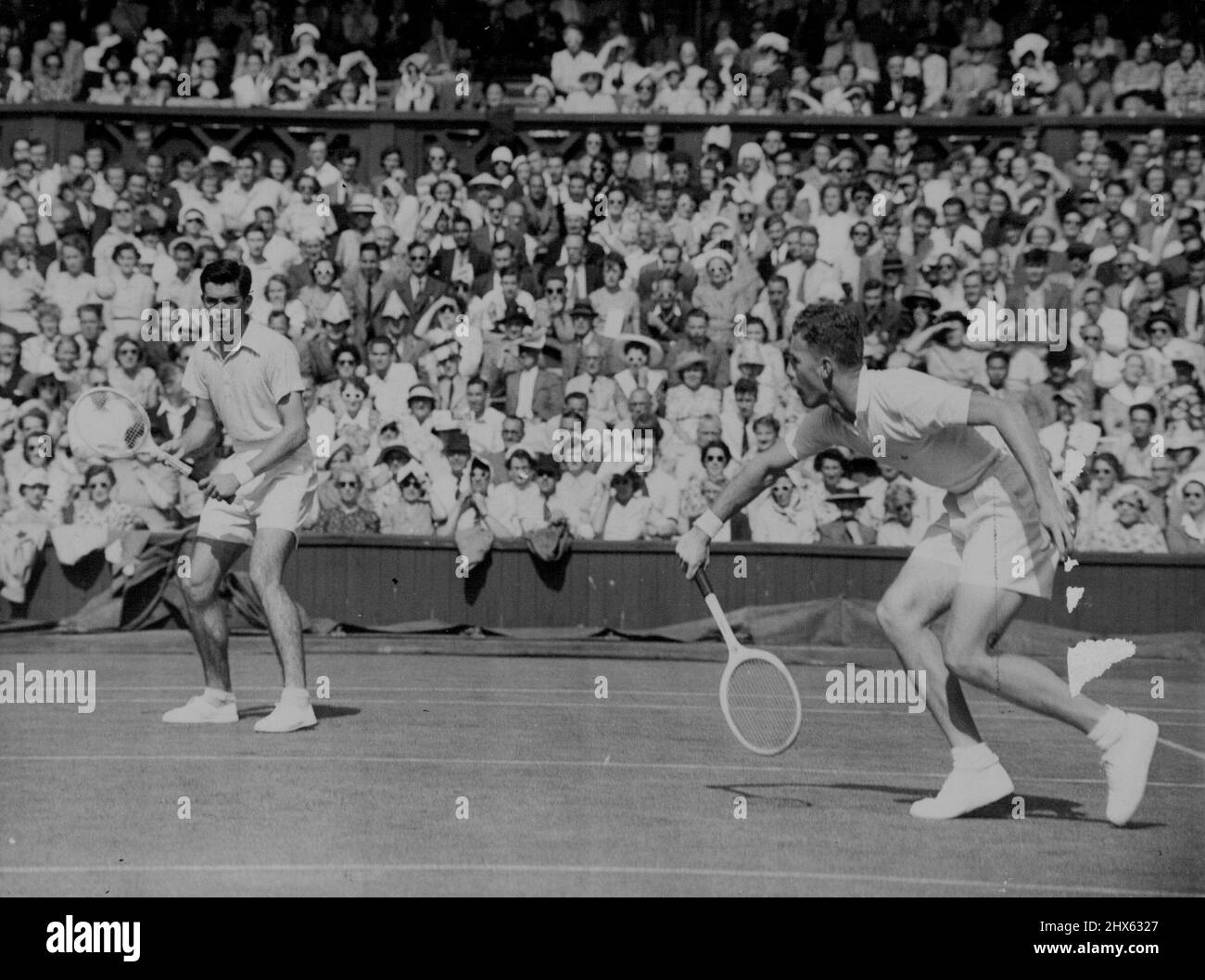 Australier am Center Court: Australier G. Worthington (rechts) spielt einen Schuss, der von seinem Partner M.G. beobachtet wird Stieg im Gentlemans Doubles Match gegen F. Kovaleski und V. Seixas auf dem berühmten Center Court in Wimbledon auf. 28. Juni 1950. Stockfoto