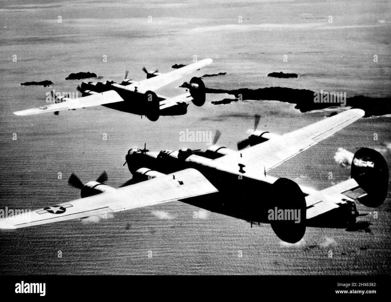 American Wings over Haha Jima mit dem Zielgebiet, das sich vor ihnen aus dem Meer erhebt, breiteten zwei Liberator-Bomber der 7. US-Armee-Luftwaffe bedrohlich ihre Flügel über Haha Jima aus Japan auf der Insel Bonin aus. Die amerikanischen Flugzeuge, die von den Stützpunkten der Marianen-Inseln aus operieren, haben regelmäßig japanische Installationen auf den Bonins und den nahegelegenen Vulkaninseln, sowohl im zentralen Pazifik, angepanzt, da die Alliierten sich immer näher an die japanische Heimat heranrücken. 19. Januar 1945. (Foto von Stockfoto