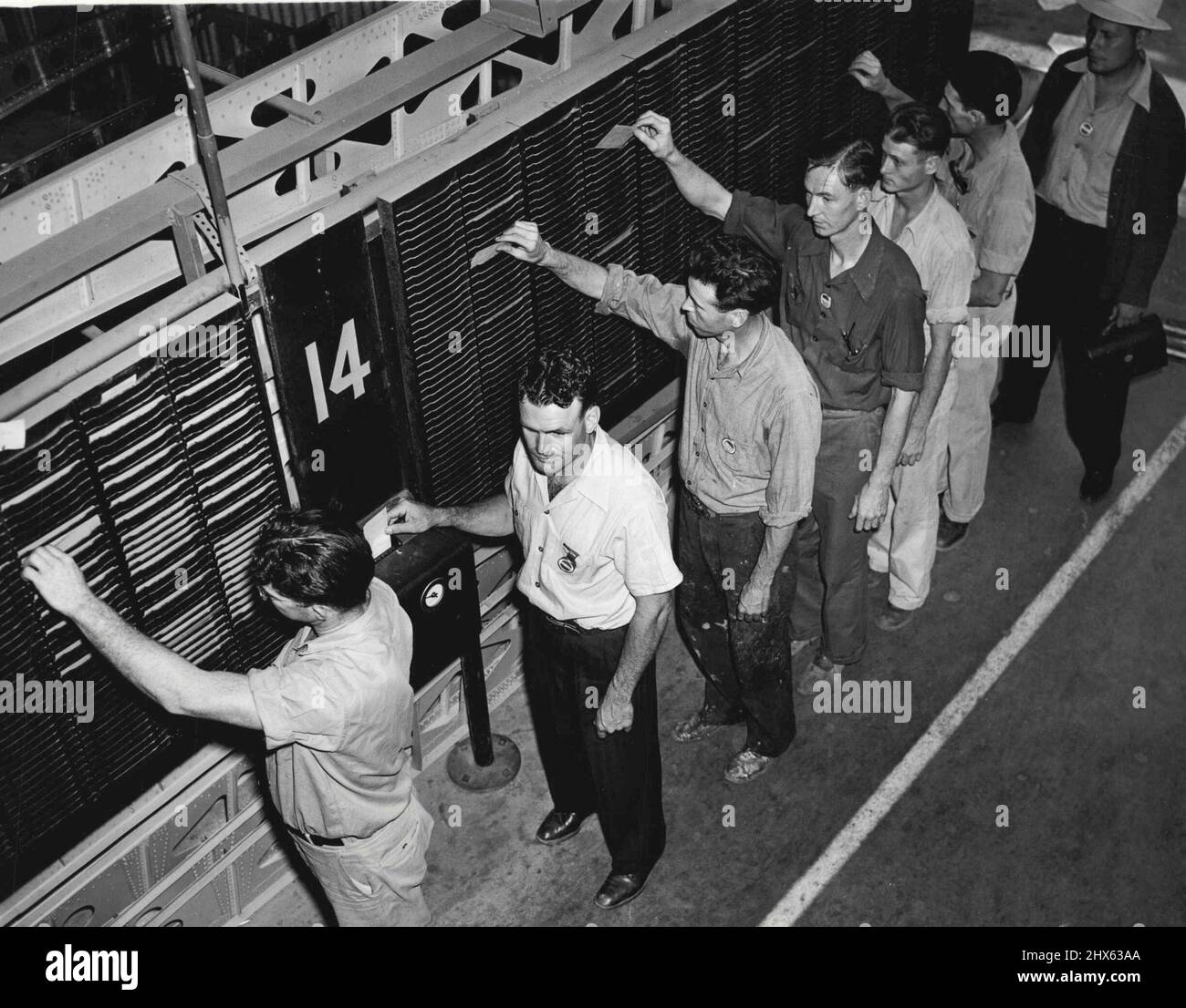 Stanzen in -- oben wird Art Palmer gezeigt (zweiter von links), der morgens über die Arbeit mit anderen Mitarbeitern berichtet. Im Werk Lockheed arbeiten mehr als nur wenige Mitarbeiter, so der Vorstand. 18. Juli 1941. (Foto von ACME). Stockfoto