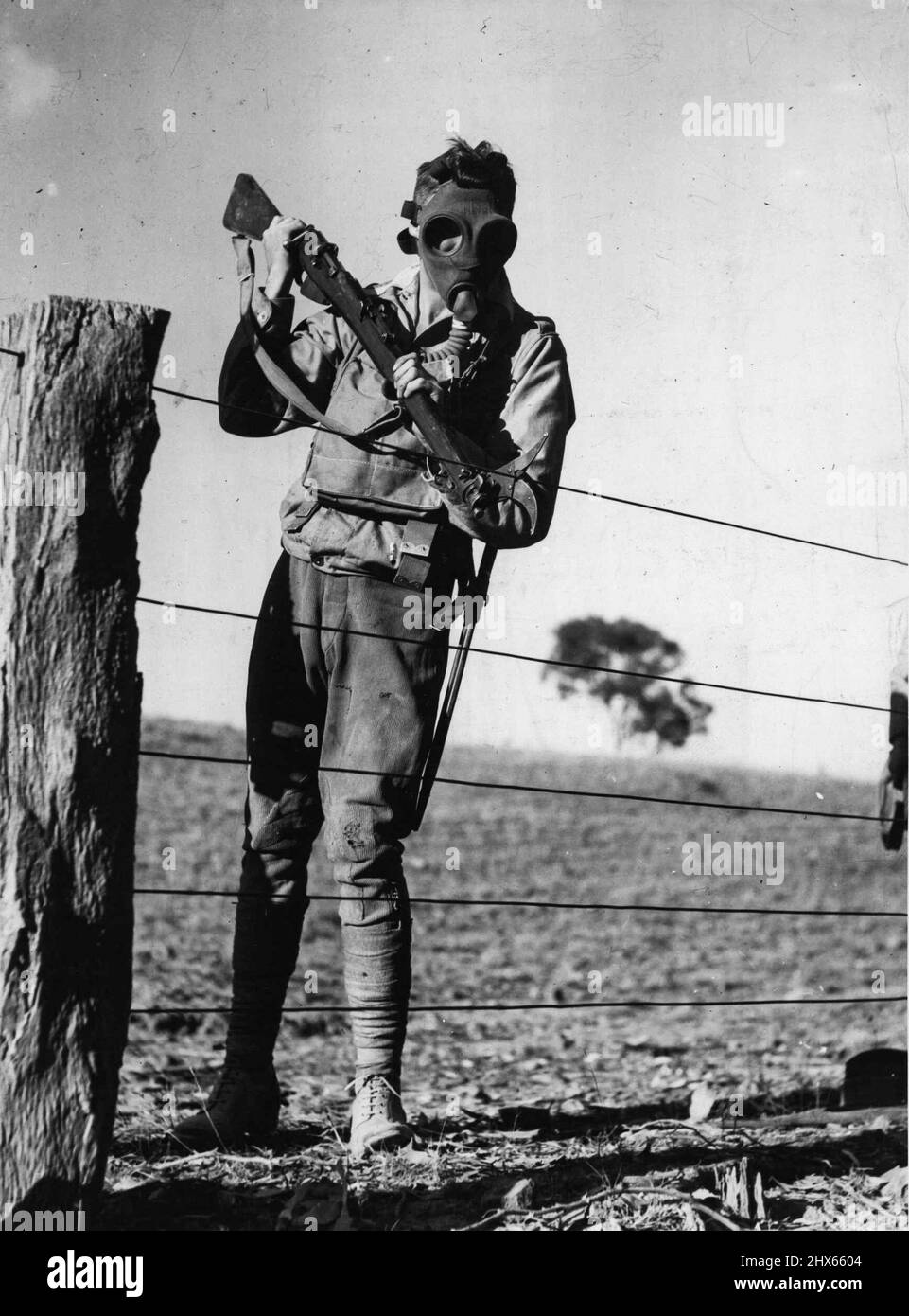 Sein Bajonett ersetzt durch einen Drahtschneider, zwang dieser maskierte Soldat der Infanteriebrigade von 4. einen Weg durch einen Zaun bei Seymour, um unterstützende Truppen an die Front zu eilen. 26. April 1937. Stockfoto