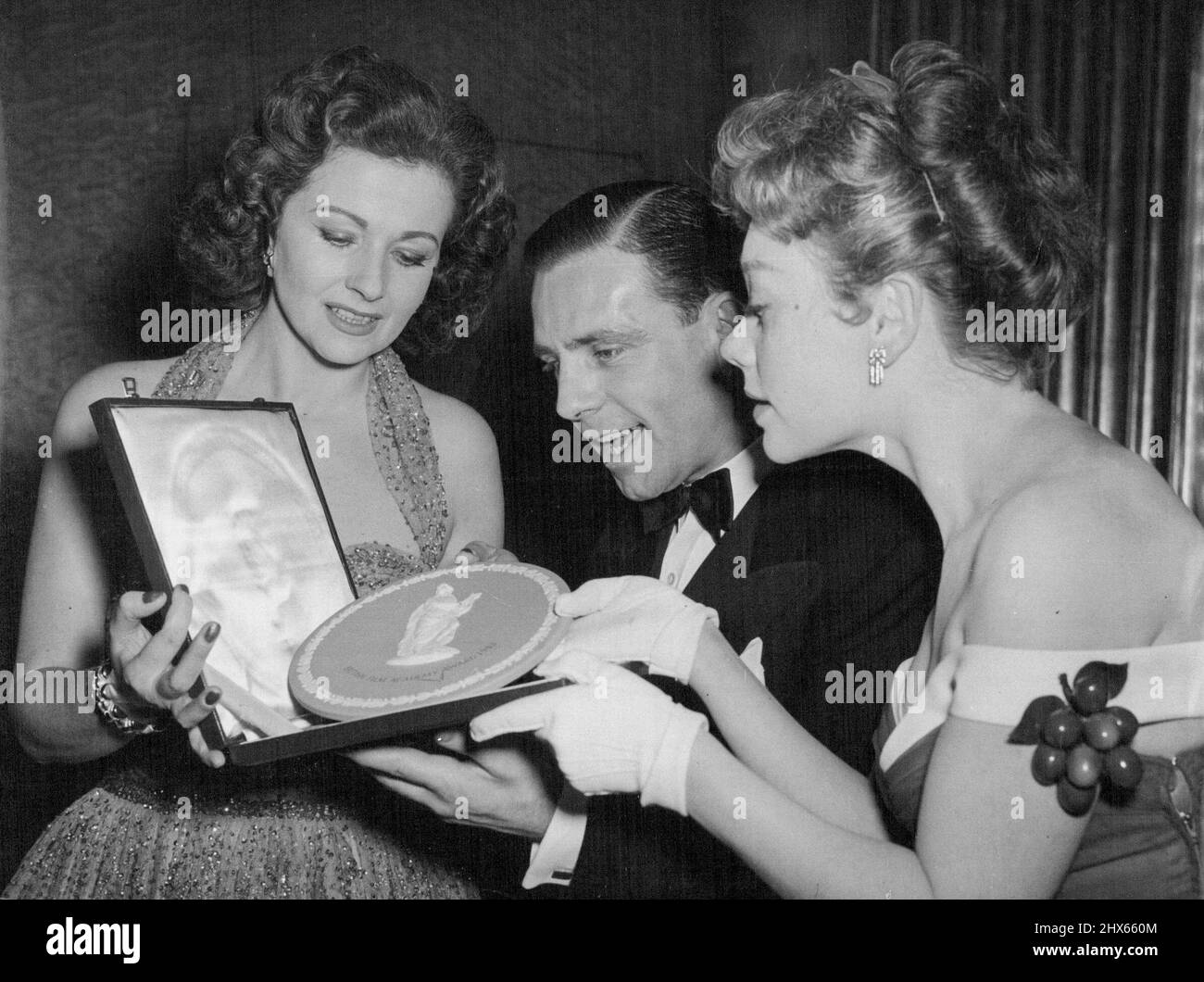 Newcomer Norman erhält seinen Award - die erfahrenen Schauspielerinnen Margaret Lockwood (links) und Glynis Johns bewundern mit Norman Wisdom den British Film Academy Award, den er gerade als „vielversprechendster Newcomer“ auf der Leinwand erhalten hat. Die Prämientafeln wurden heute Abend (Donnerstag) auf dem Odeon, Leicester Square, verliehen. 25. März 1954. (Foto von Reuterphoto). Stockfoto