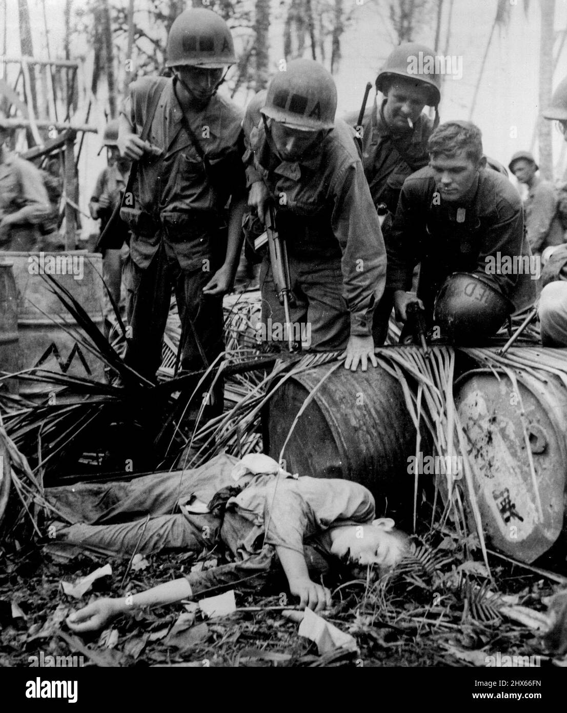 Ein toter Japaner liegt unter den von den Feinden bezischten Ausrüstungsgegenden, während sich amerikanische Truppen während des Angriffs auf Hollandia im niederländischen Neuguinea am Strand bewegen. 25. April 1944. (Foto vom Department of Information Picture). Stockfoto