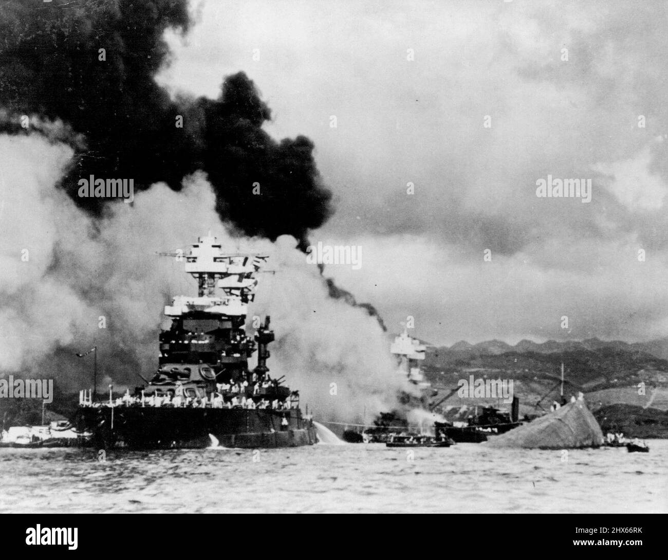 Vertäut links vom gekenppten Schlachtschiff, U.S.S. Oklahoma, das von Jap Dive- und Torpedo-Bombern während des Sneak-Angriffs auf Pearl Harbor im Dezember 7. gestrahlt wurde, ist das 31.500-Tonnen-Schlachtschiff U.S.S. Maryland, das beim Angriff leicht beschädigt wurde. Dieses Foto, das kurz nach dem Angriff aufgenommen wurde, wurde gerade vom Navy Department in Washington veröffentlicht. Die Maryland war eines der ersten Schiffe, die sich nach dem Jap-RAID der Flotte anschliessen. 4. Februar 1943. (Foto von U.S. Navy Photo). Stockfoto