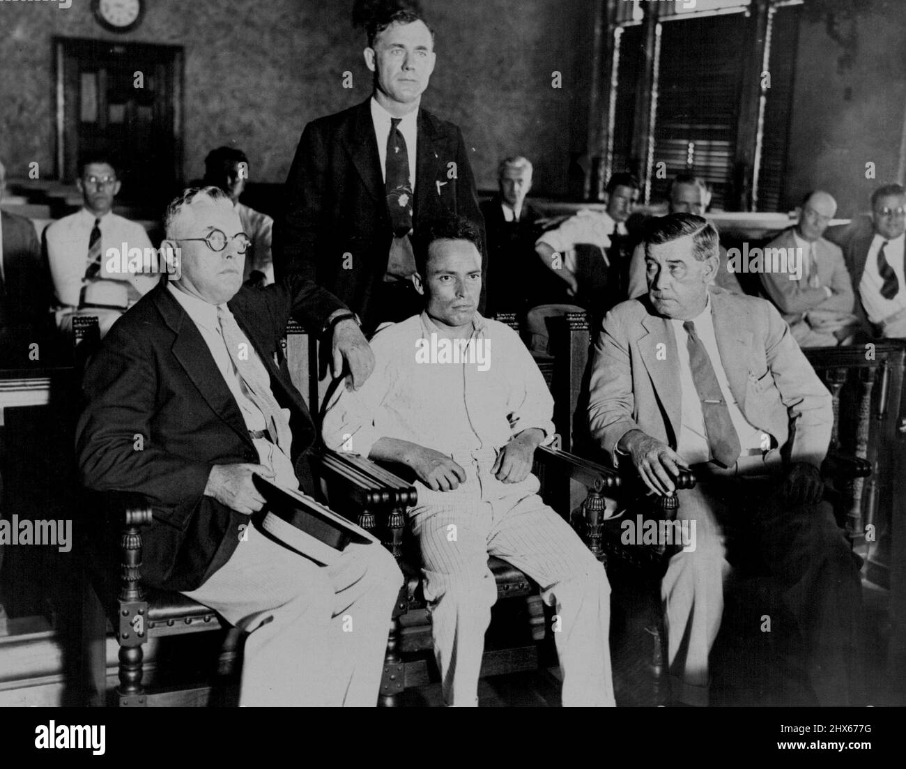 Zangara im Strafgerichtshof von Miami -- Giuseppe Zangara, der kleine Hackensack, N.J. Maurer, im Strafgerichtshof, Miami, Fal., umgeben von Abgeordneten, Warten darauf, für seinen Versuch, den designierten Präsidenten Roosevelt zu ermorden, und die Verwundung des Bürgermeisters Cermak aus Chicago und von vier anderen in der Nacht vom 15. Februar angeklagt zu werden. Die Vertagung wurde verschoben. Es wurde berichtet, dass eine Bewegung zu Fuß in der Stadt Florida zu Lynch ihn war. 17. Februar 1933. (Foto von Associated Press Photo). Stockfoto
