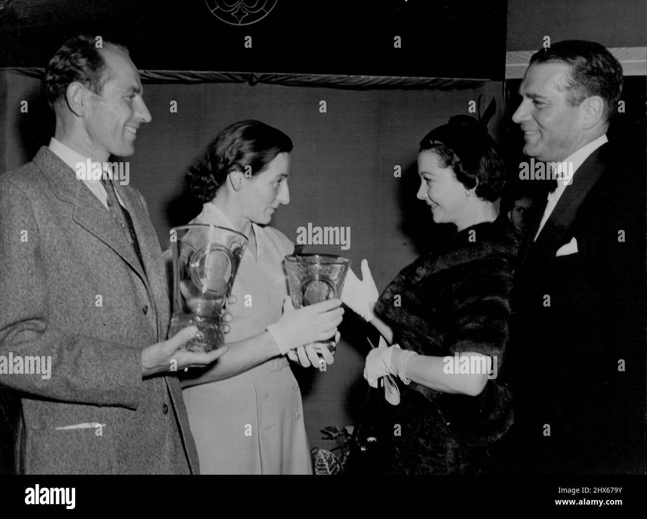 Zatopeks Geschenk tschechisches Glas an Oliviers -- Sir Lawrence und Lady Olivier empfangen die Glasvasen von Emil Zatopek und seiner Frau. Emil Zatopek, der berühmte Langstreckenläufer, und seine Frau überreichten Sir Lawrence und Lady Olivier gestern Abend zwei Glasvasen mit Porträts von Sir Lawrence und seiner Frau. Sie sind das Werk des tschechischen Künstlers Lobmeyr. Die Präsentation fand auf der Bohemian Glass Ausstellung in London statt. 14. Oktober 1955. (Foto von Paul Popper Ltd.). Stockfoto