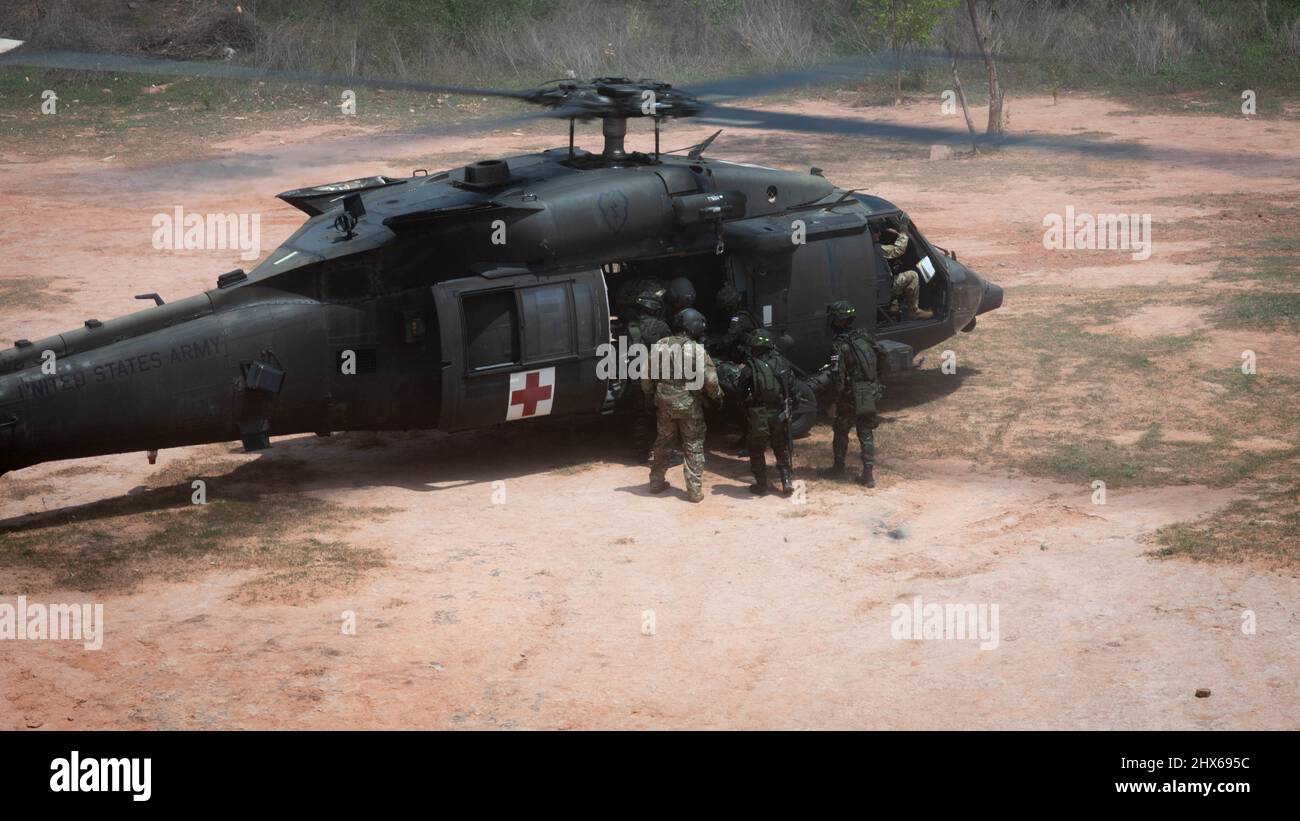 Ein Flugarzt der US-Armee, 2. Assault Helicopter Bataillon, 25. Aviation Regiment, 25. Infantry Division, weist Royal Thai Soldaten an, die während des Medivac Trainings einen simulierten Patienten auf einen UH-60 Black Hawk laden, 7.. März 2022, Fort Thanarat, Thailand. Medivac-Training ist ein Schwerpunkt von Hanuman Guardian 22 (HG22). HG22 ist Teil der Pacific Pathways-Serie, die darauf ausgelegt ist, die Bereitschaft zu erhöhen, Beziehungen zu stärken und Interoperabilität zwischen Dienstmitgliedern der US-Armee und der Royal Thai Army zu entwickeln. (USA Air Force Photo von Tech. Sgt. Michael Mason) Stockfoto