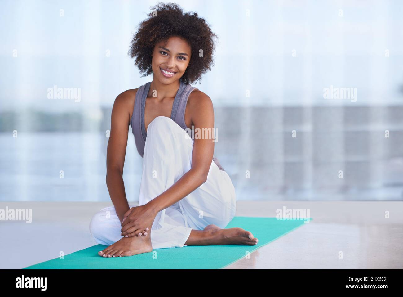 Übung lässt mich lächeln. Aufnahme einer attraktiven jungen Frau, die auf einer Trainingsmatte sitzt. Stockfoto