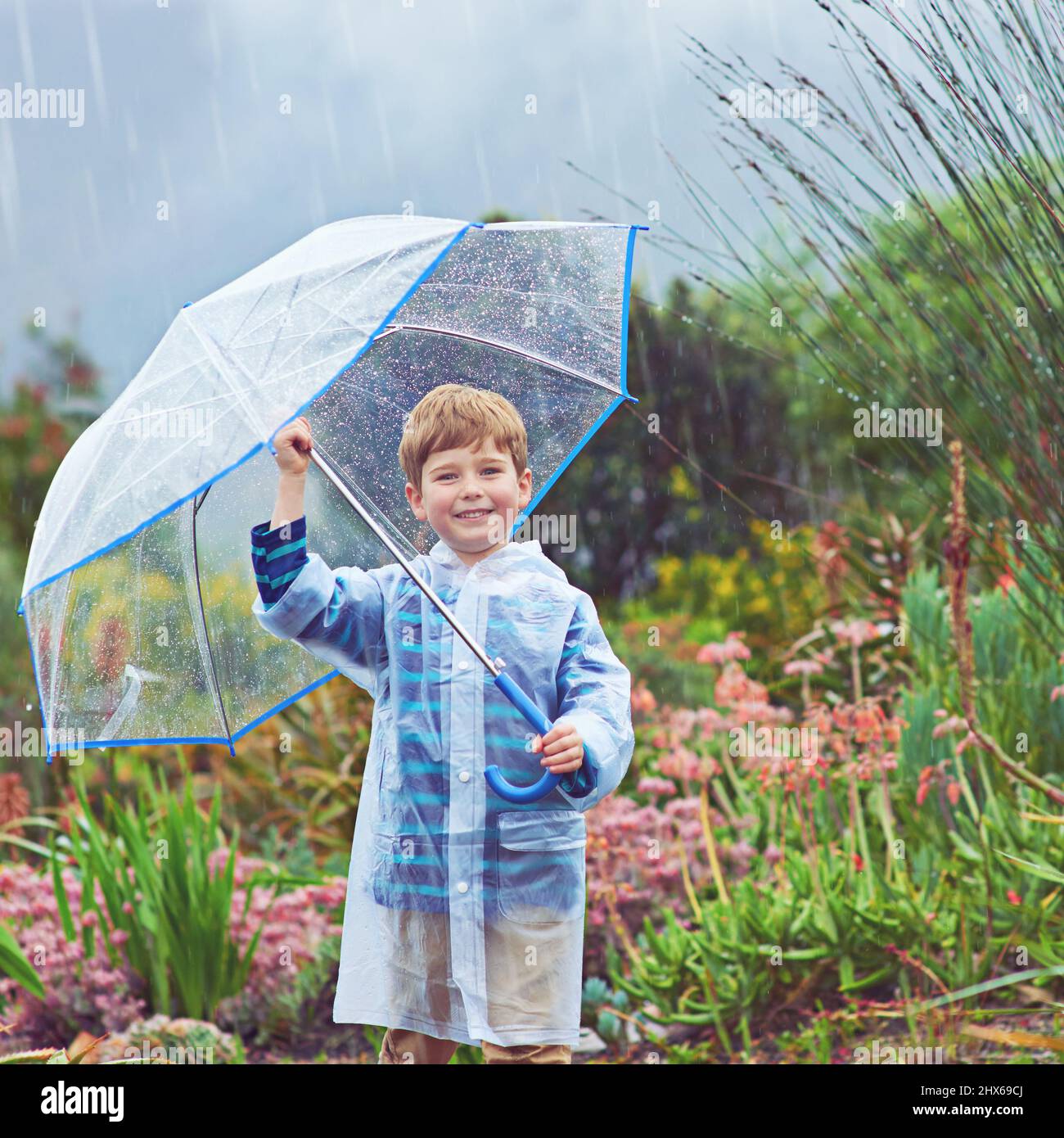 Ich liebe den Regen fast so sehr wie mein Garten. Beschnittenes Porträt eines Jungen, der draußen im Regen steht. Stockfoto