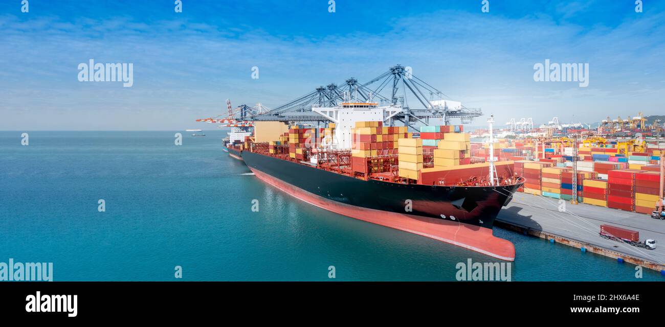 Kranverladung Frachtcontainer von LKW zu Containerschiff im internationalen Terminal logistic Seehafenkonzept Frachtschifffahrt per Schiff Stockfoto