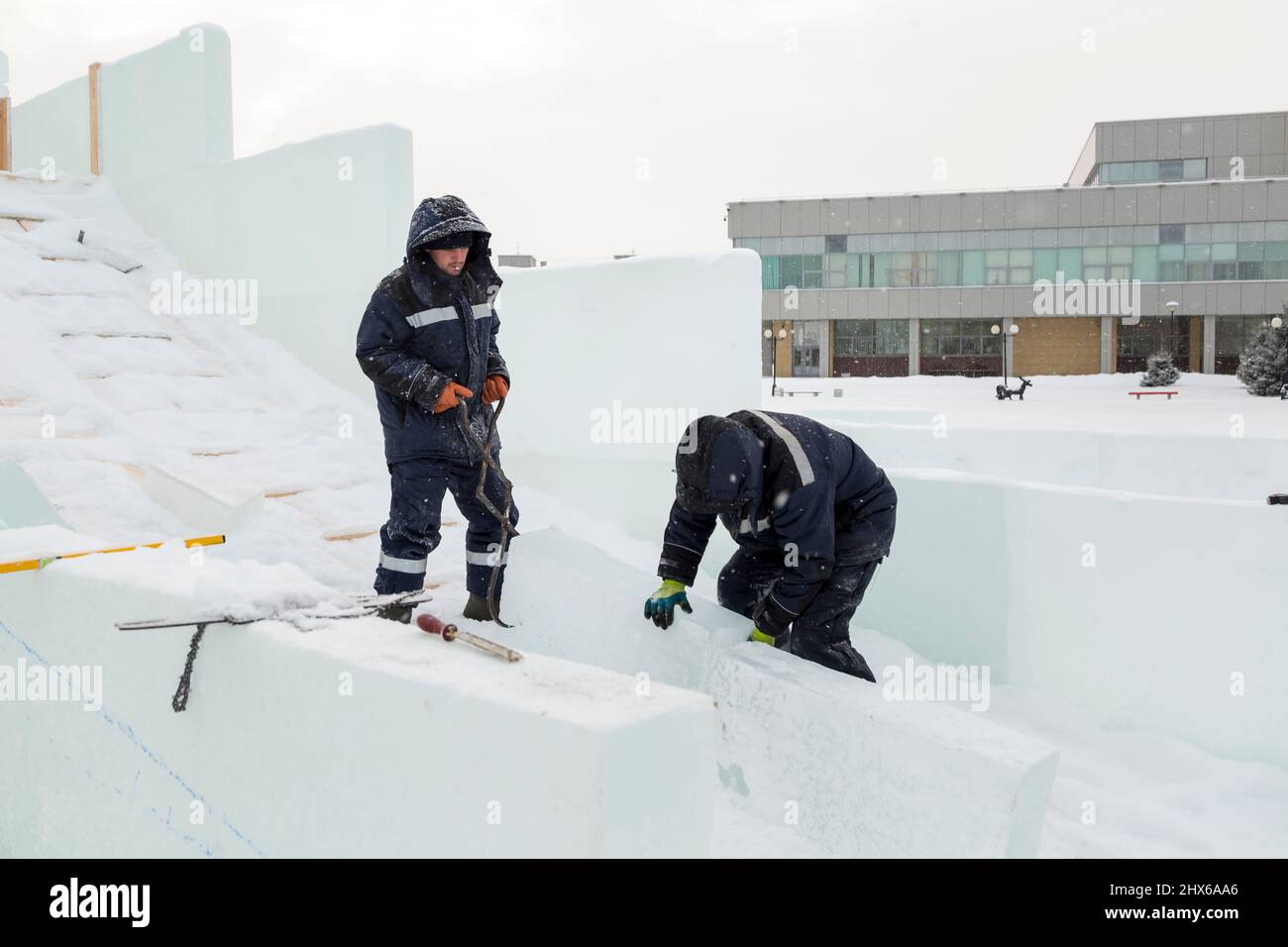 Der Arbeitnehmer zieht den Eisblock um das Ice Camp Montageplatz mit Zange Stockfoto