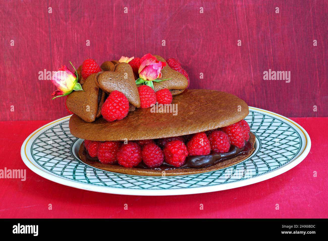 Ein riesiger Makkaronkuchen aus Schokolade mit frischen Himbeeren und Rosenblüten Stockfoto