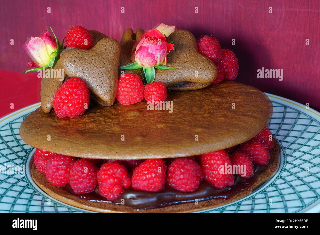 Ein riesiger Makkaronkuchen aus Schokolade mit frischen Himbeeren und Rosenblüten Stockfoto