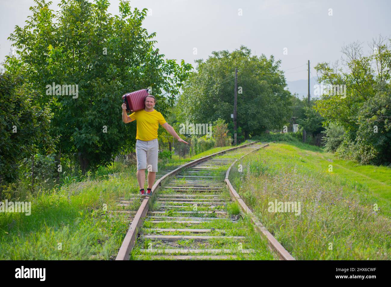 Ein Junge auf seiner Schulter trägt einen roten Koffer Stockfoto