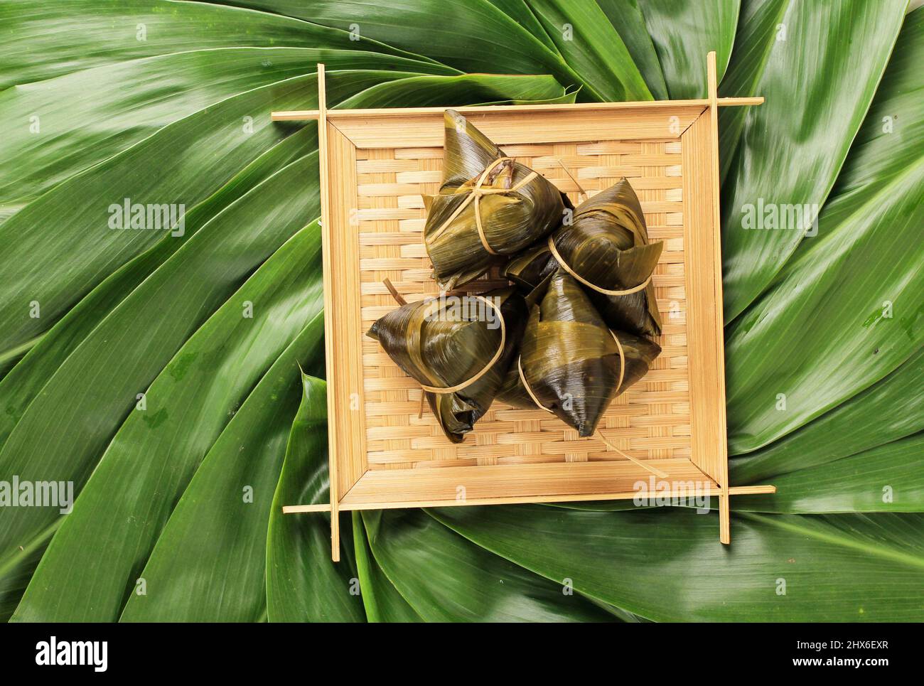 Reisdumpling, Zongzi oder Bacang, traditionelle chinesische Küche auf grünem Blatt Hintergrund des Drachenbootfestes, Duanwu Festival, Draufsicht, Flat Lay Desig Stockfoto