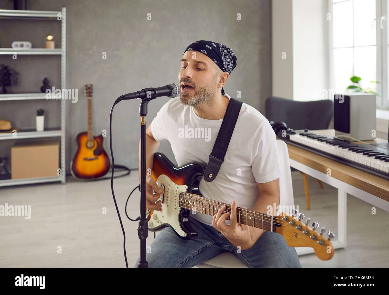 Männlicher Musiker spielt Gitarre und singt auf dem Mikrofon Stockfoto