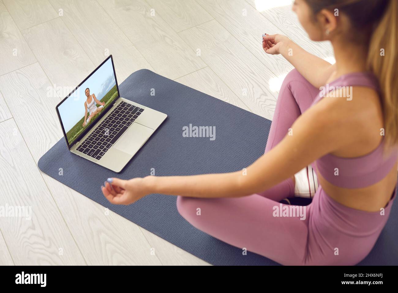 Frau, die sich eine Videostunde über Meditation ansieht oder Yoga mit einer Online-Lehrerin praktiziert Stockfoto