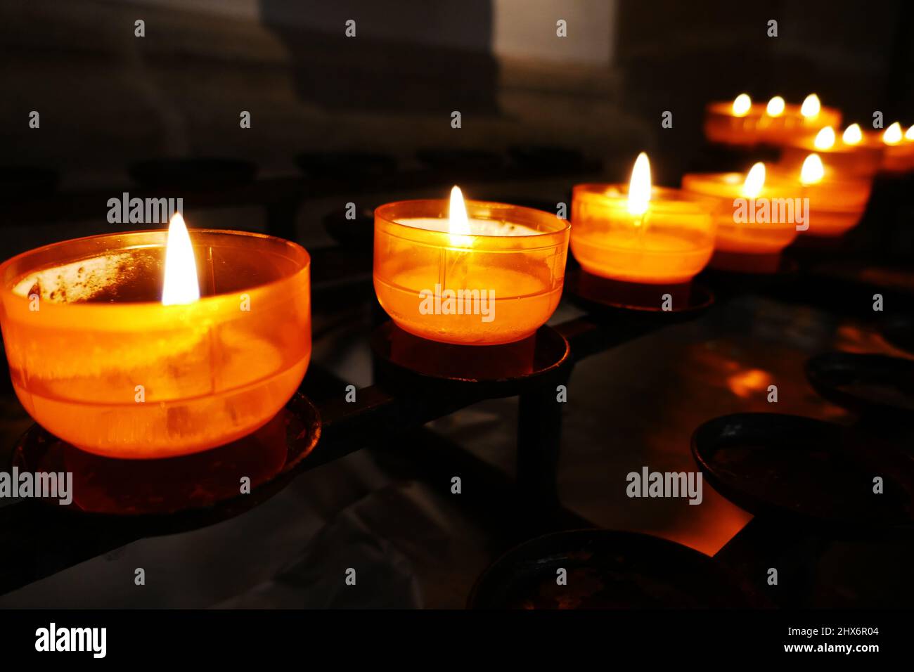Reihe mit gelben Gebetsleuchten in einer römisch-katholischen Kirche Stockfoto